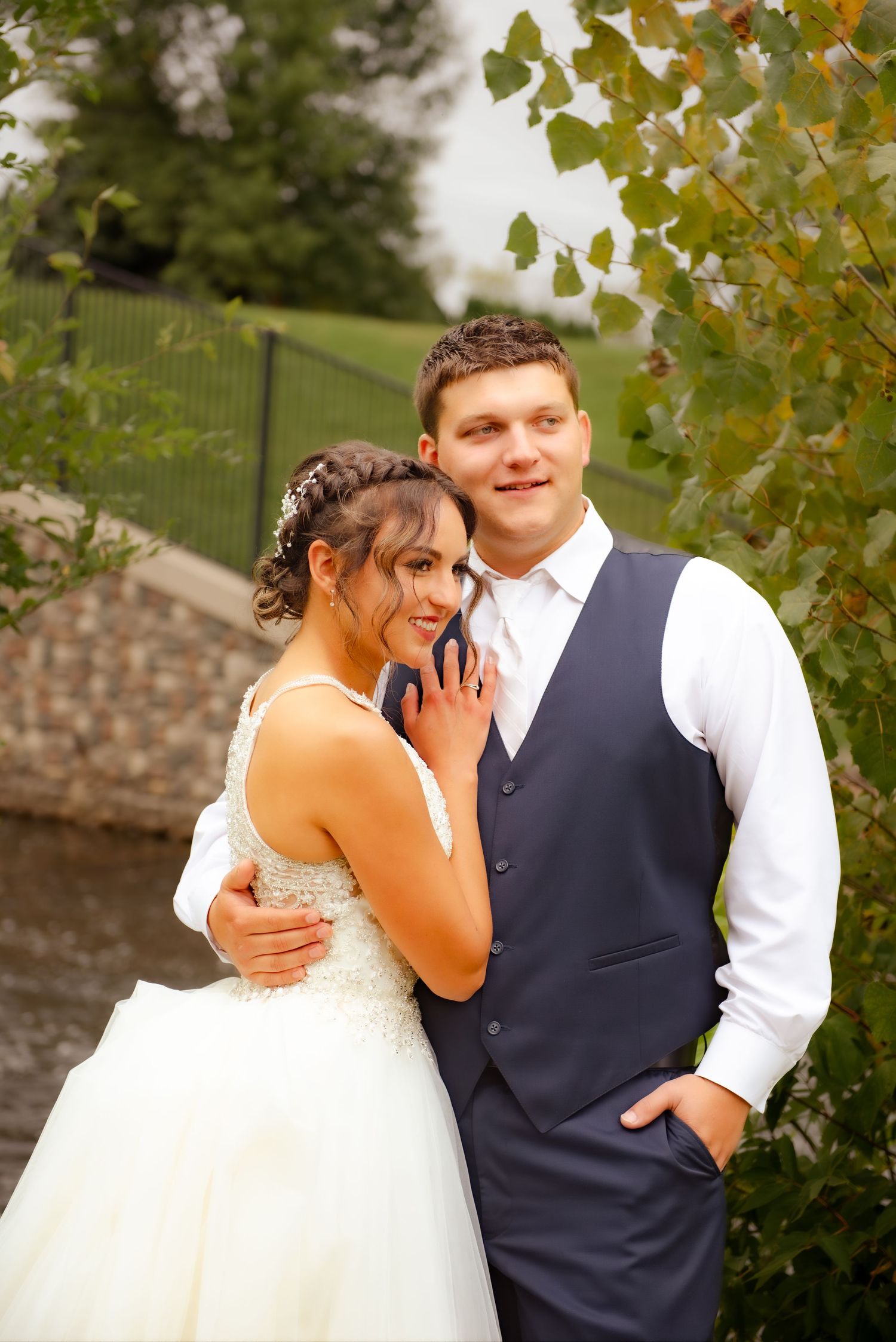 A tender moment between newlyweds posing outdoors with autumn leaves in the background.