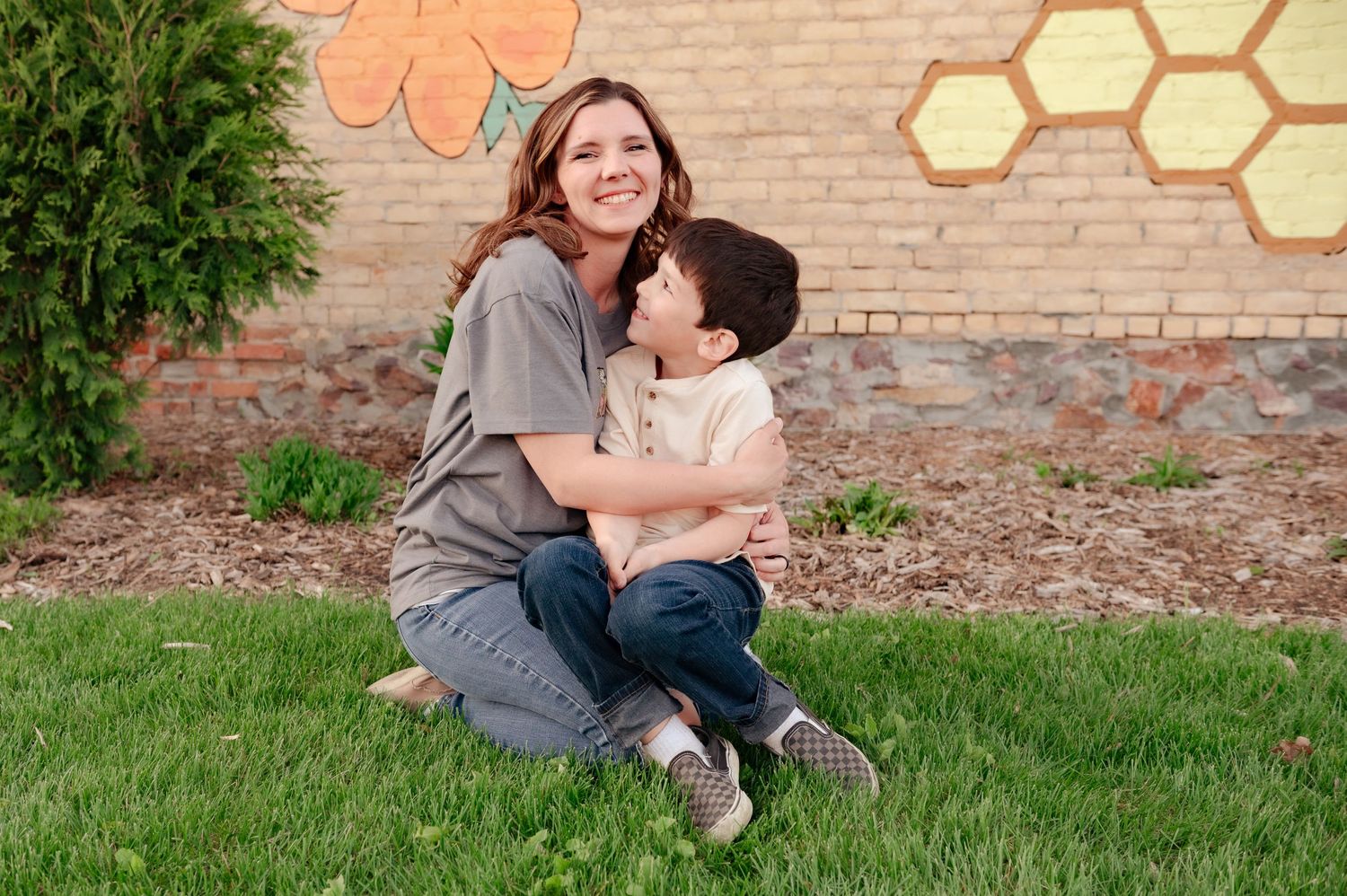 Joyful outdoor portrait session with playful embraces in front of decorative wall art.