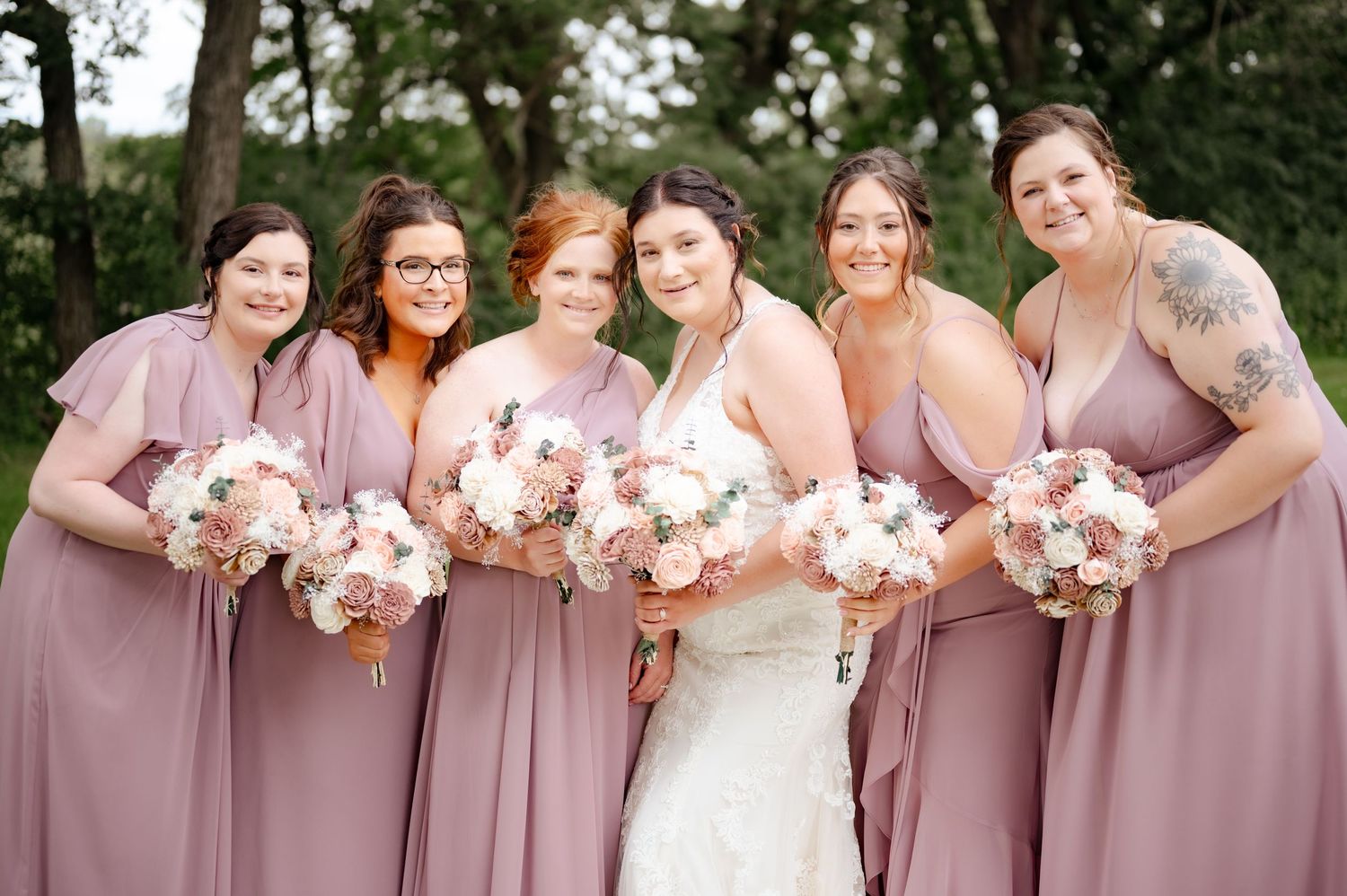 Bridal party holding beautiful pink and white bouquets while wearing dusty rose colored dresses.