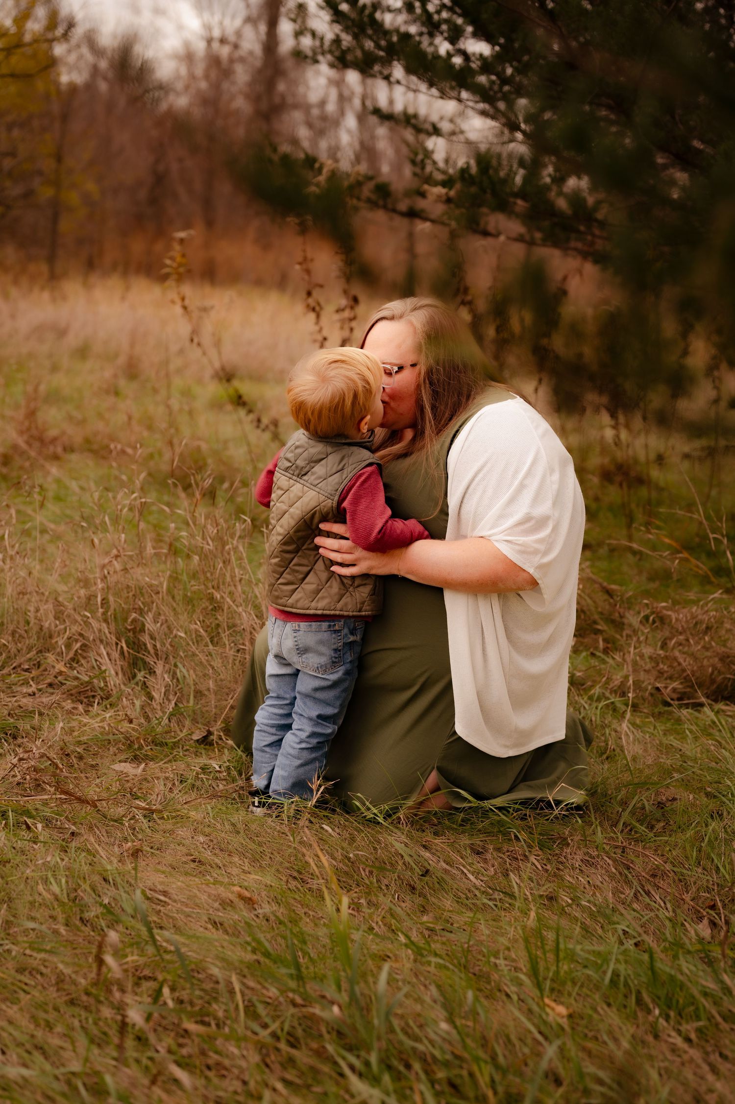 A touching moment between parent and child sitting together in a grassy field during autumn.