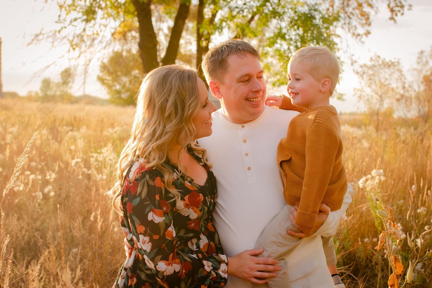 Joyful family portrait in autumn field during golden hour.