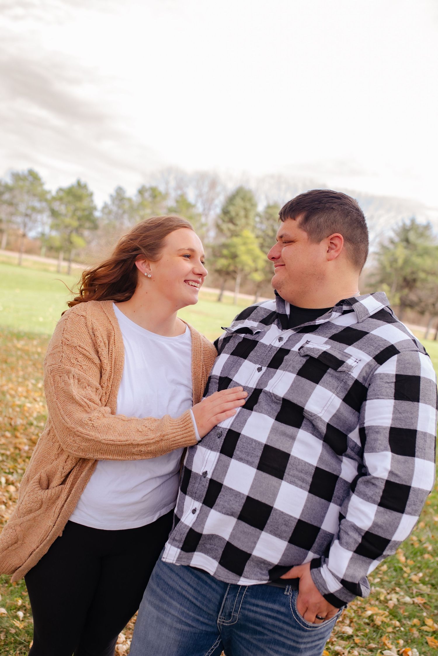 A couple sharing an intimate moment outdoors while wearing casual fall attire.