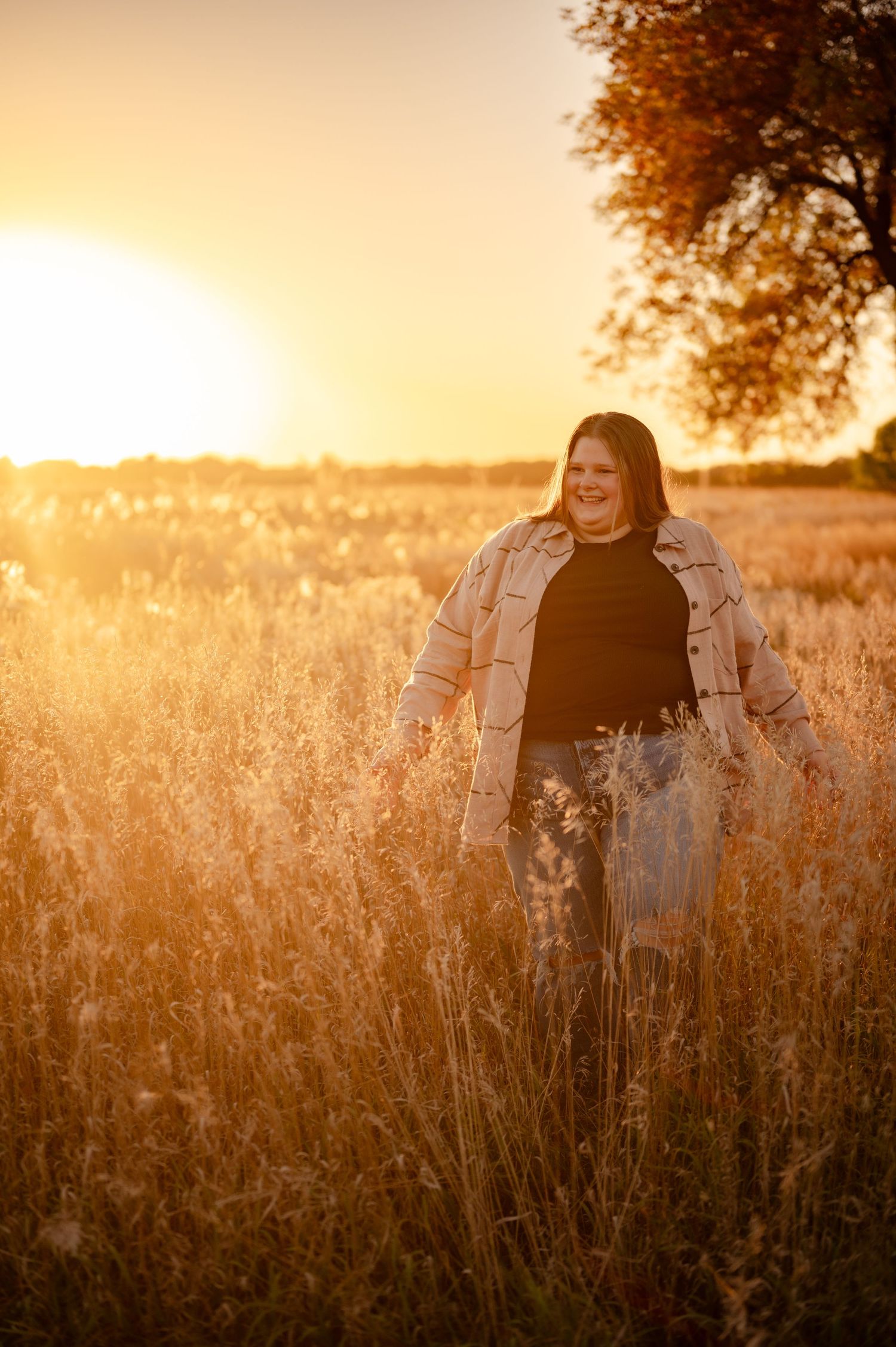 Golden sunset light illuminates tall grass in field during outdoor portrait session.