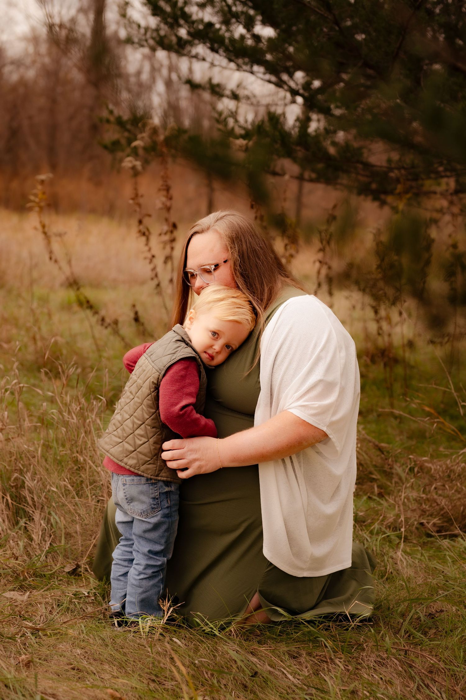 A touching outdoor moment in nature shows a gentle embrace between two figures in casual clothing.
