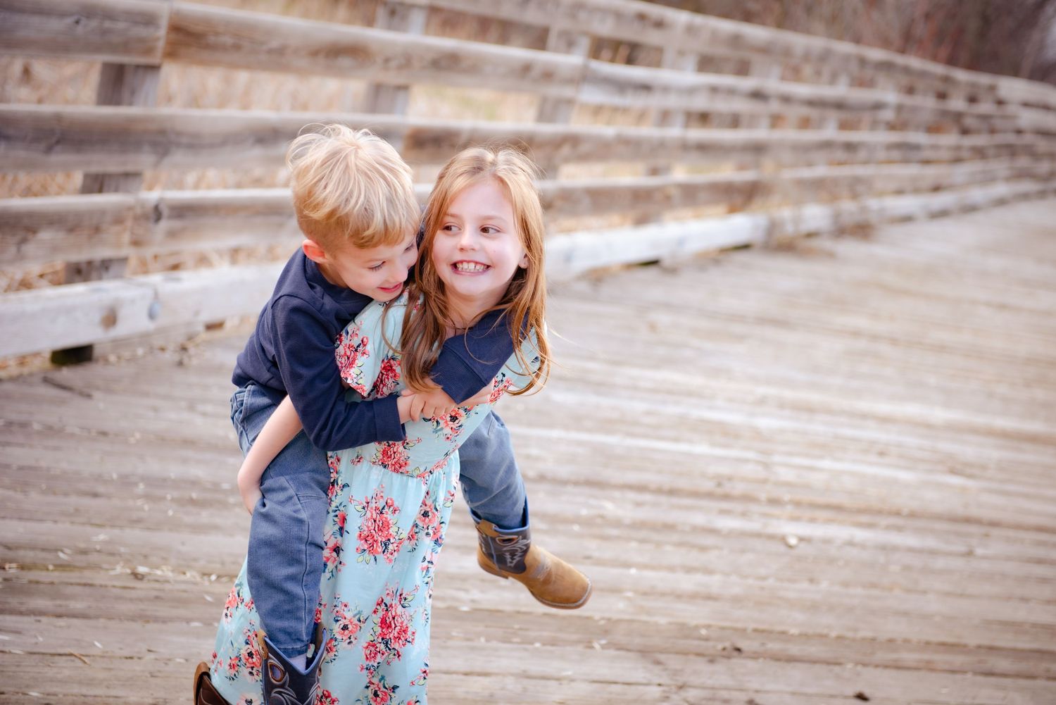 Two playful children interacting and laughing together on a wooden bridge.