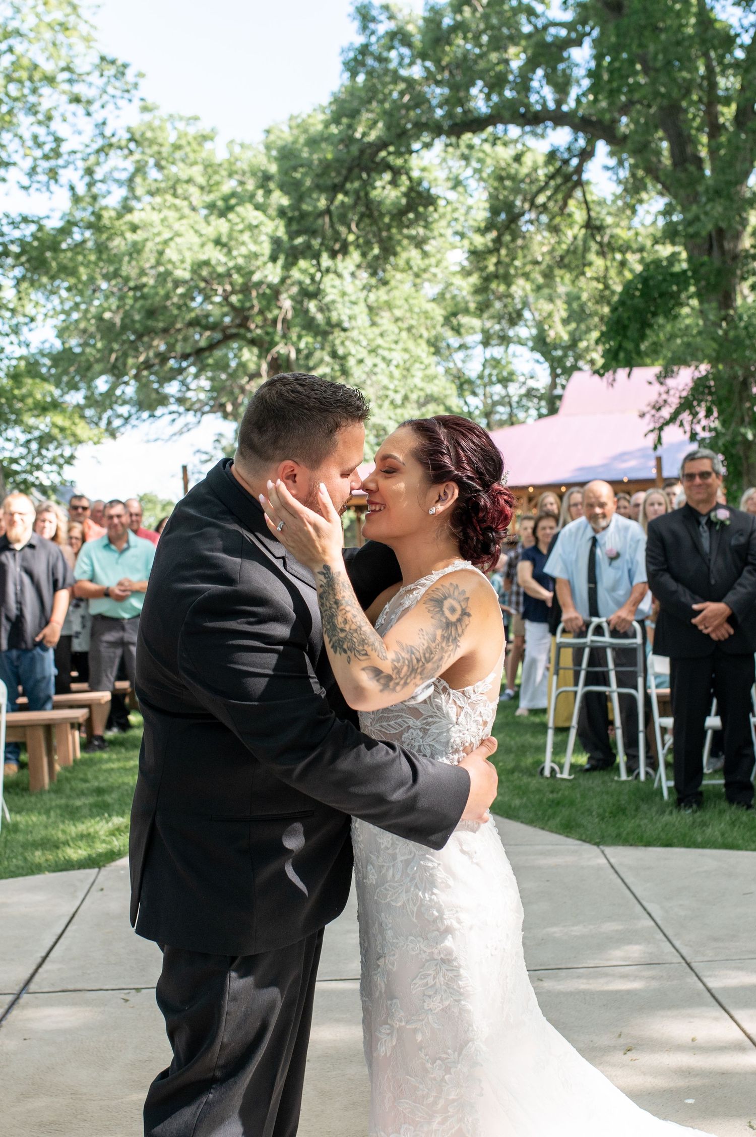 A couple shares an intimate moment during their first dance at an outdoor summer wedding.
