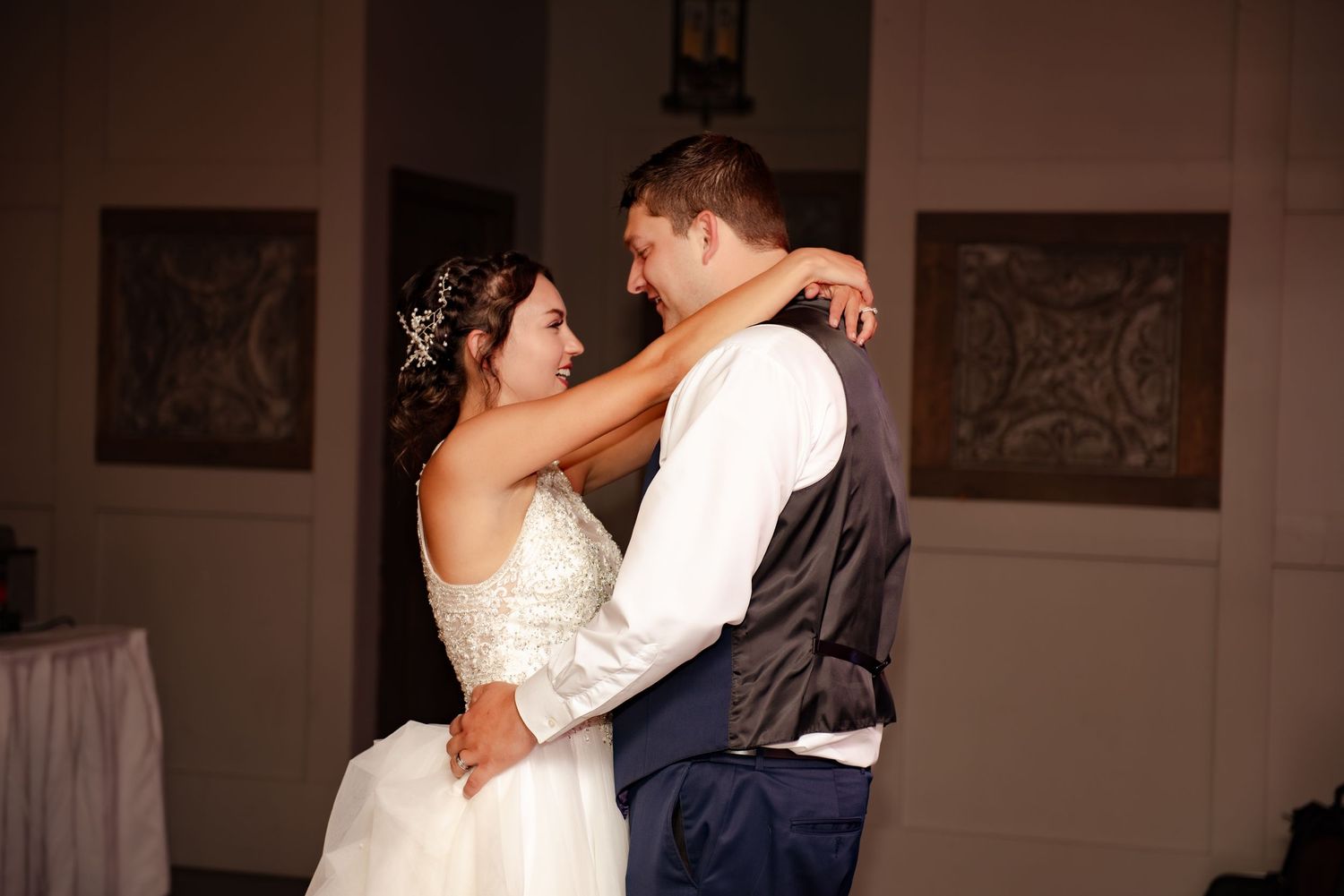A romantic dance moment captured in warm lighting at an indoor wedding reception venue.