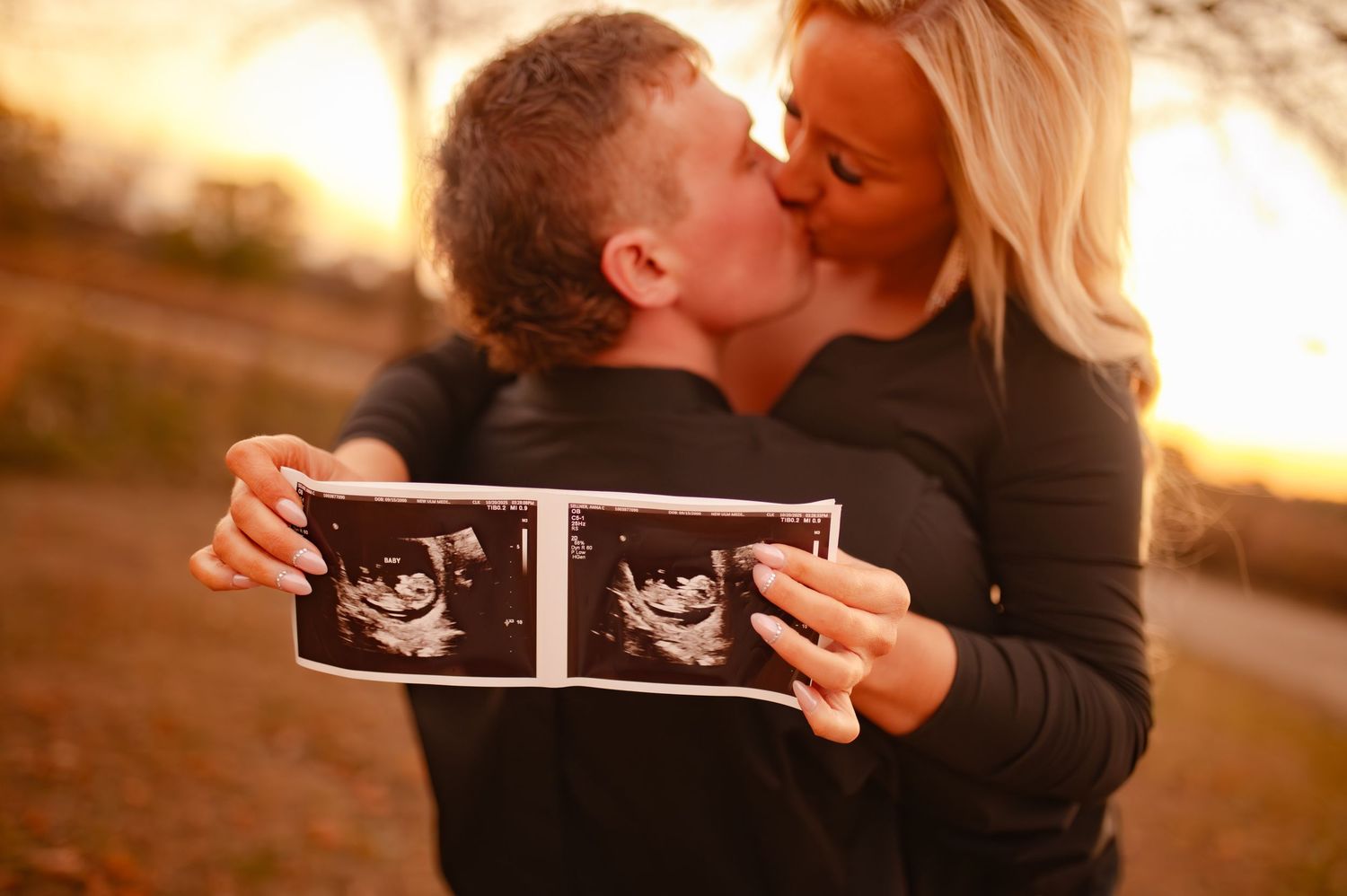 Couple looking at ultrasound images together during outdoor pregnancy announcement photoshoot.