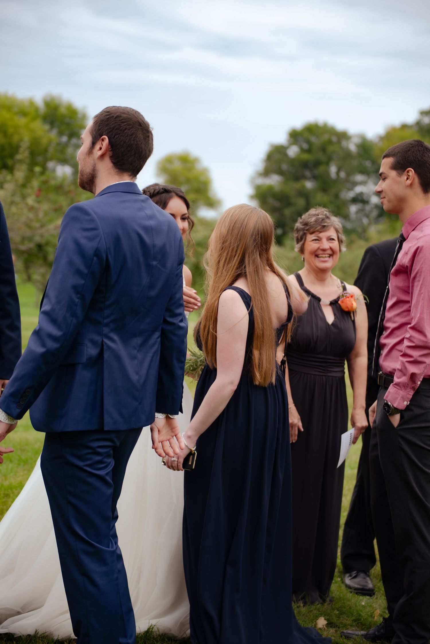Wedding guests gathered on a lawn in formal attire during an outdoor celebration.