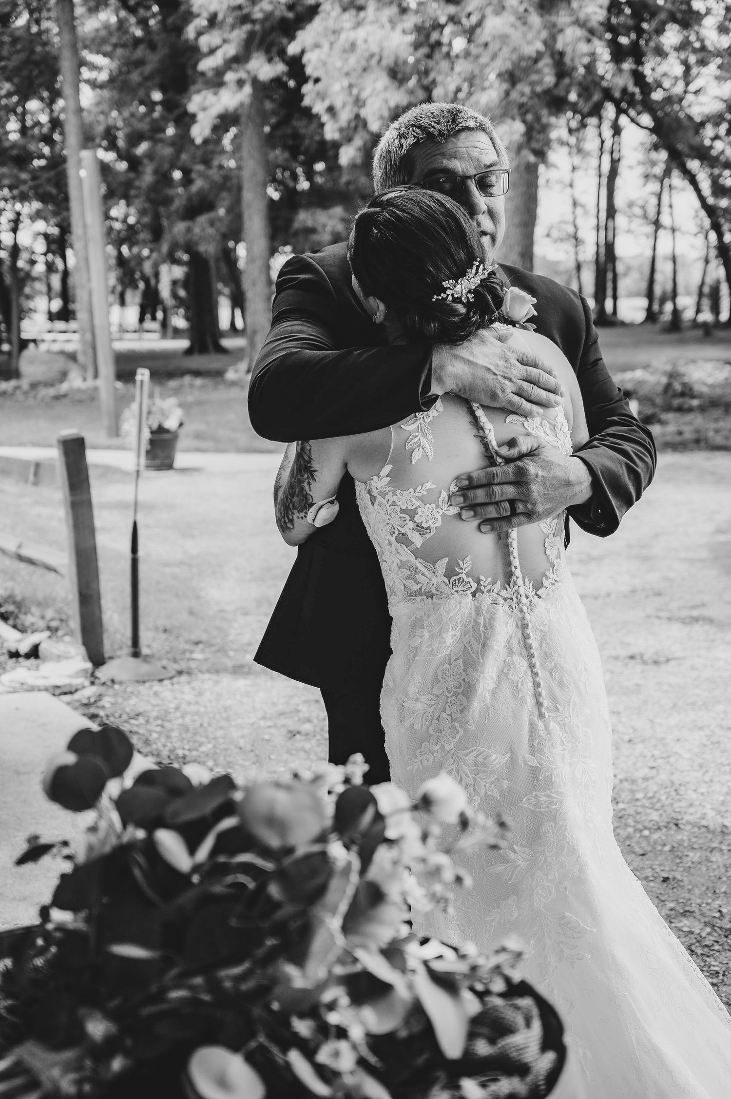 A black and white photo capturing an intimate wedding embrace outdoors.