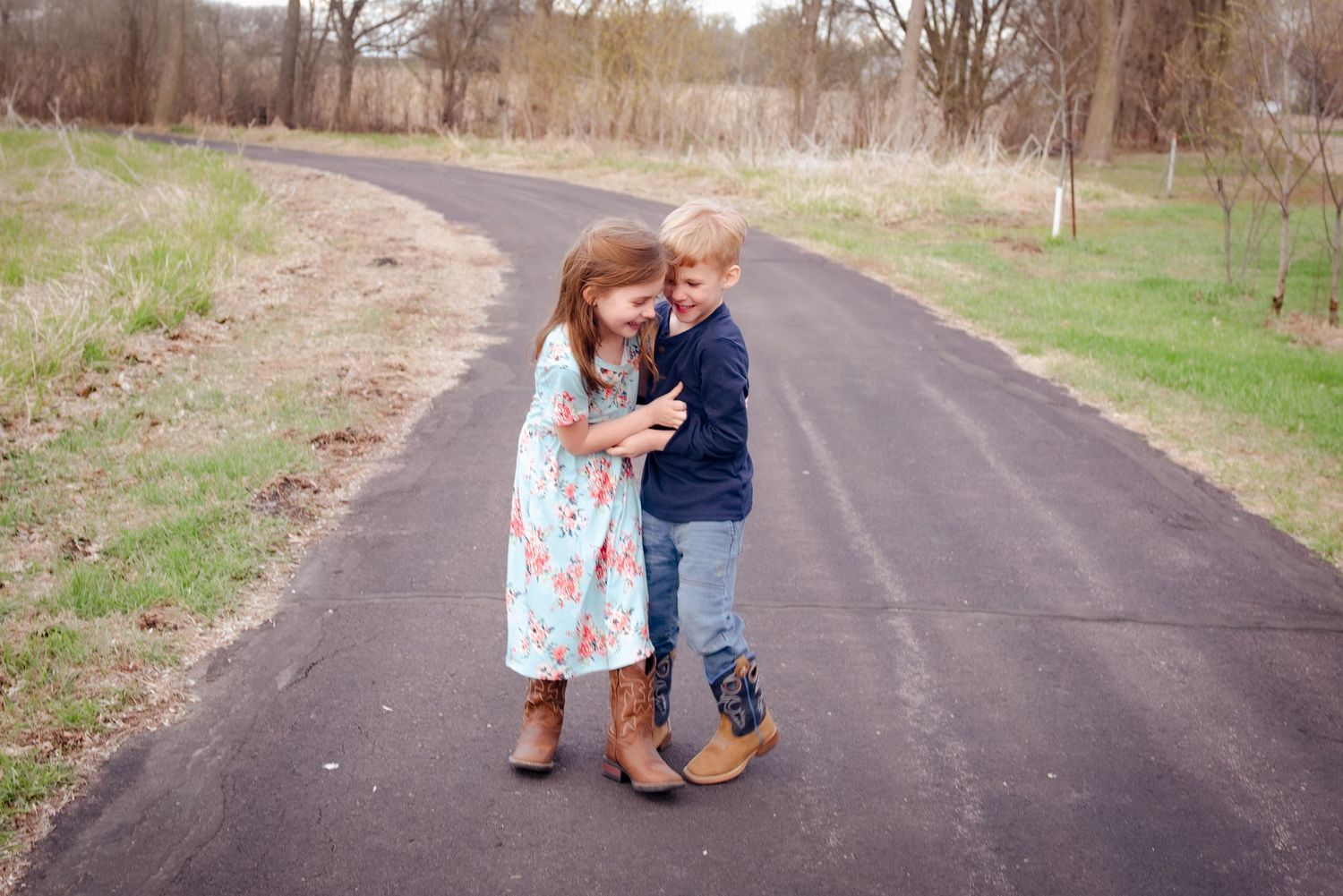 Two children sharing a sweet moment together on a paved walkway.