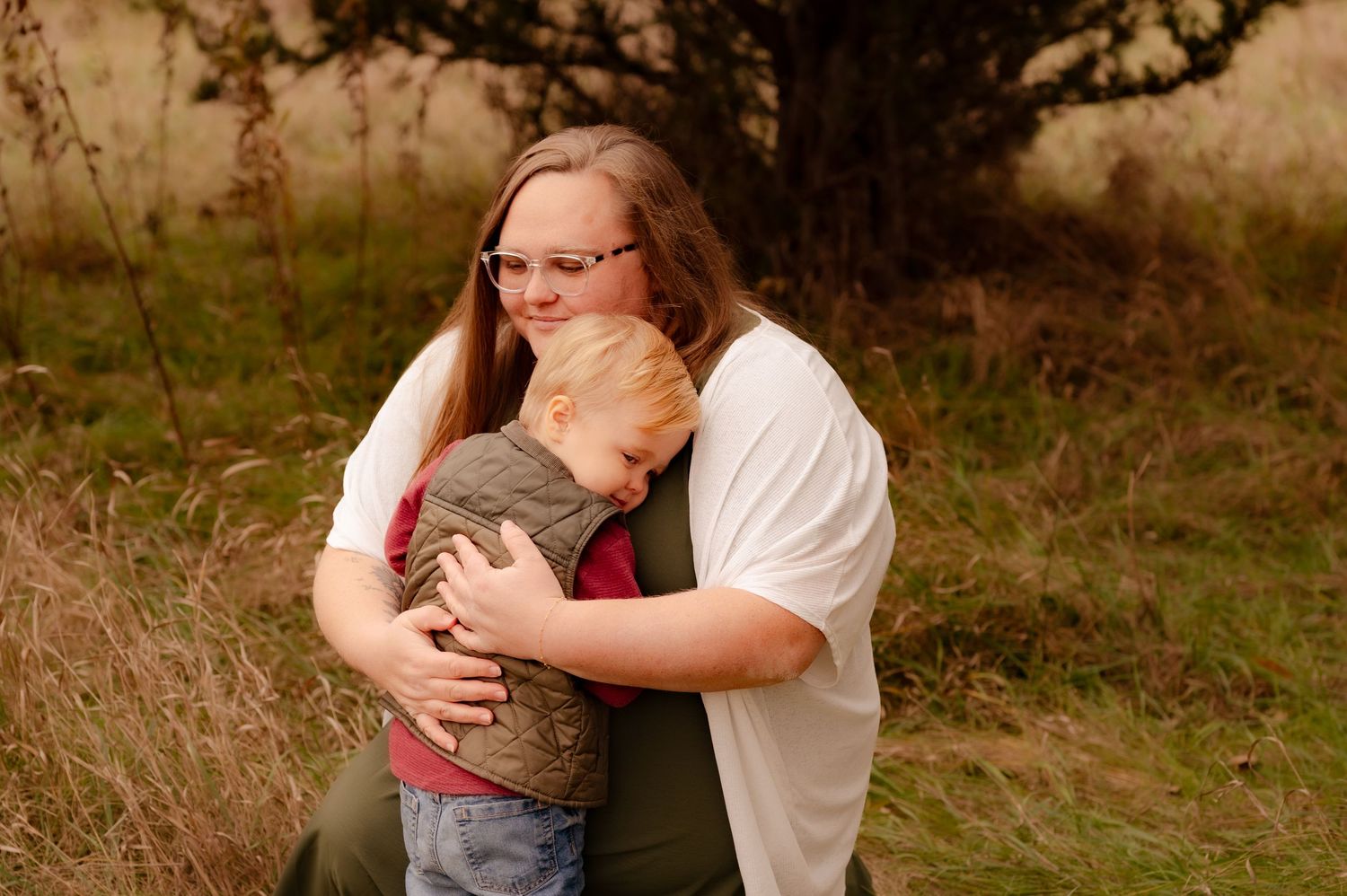 A couple embraces tenderly in an outdoor setting with warm autumn colors in the background.