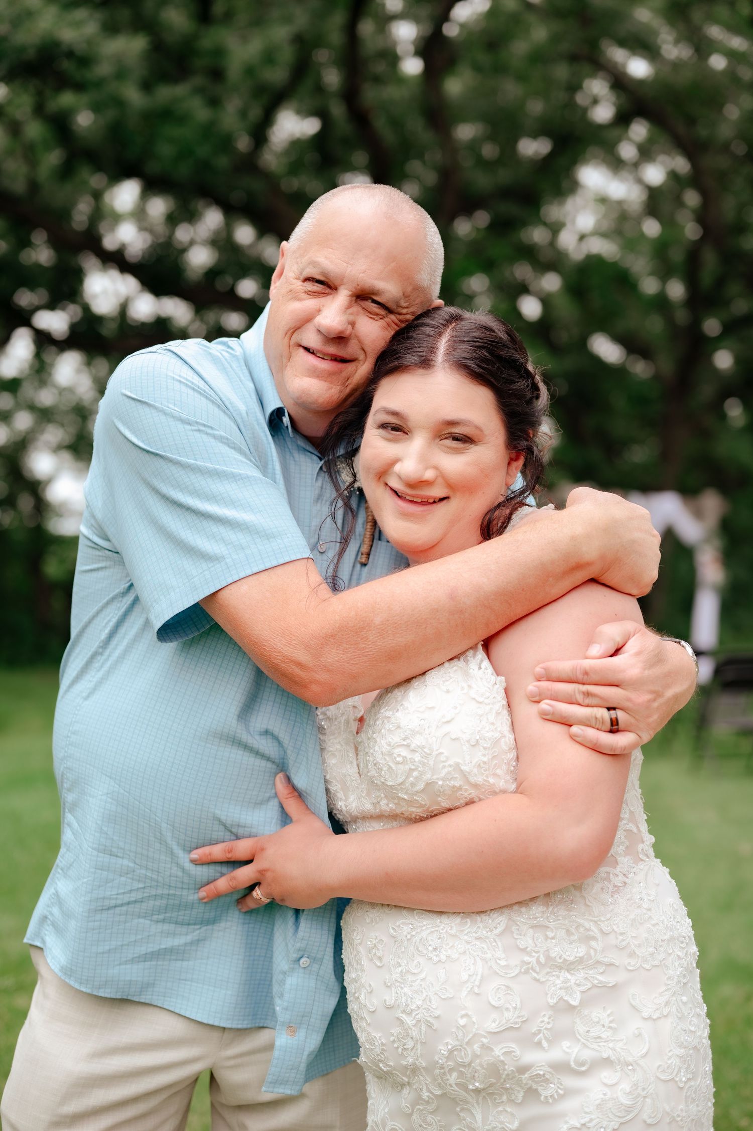 Tender embrace captured outdoors during wedding celebration.