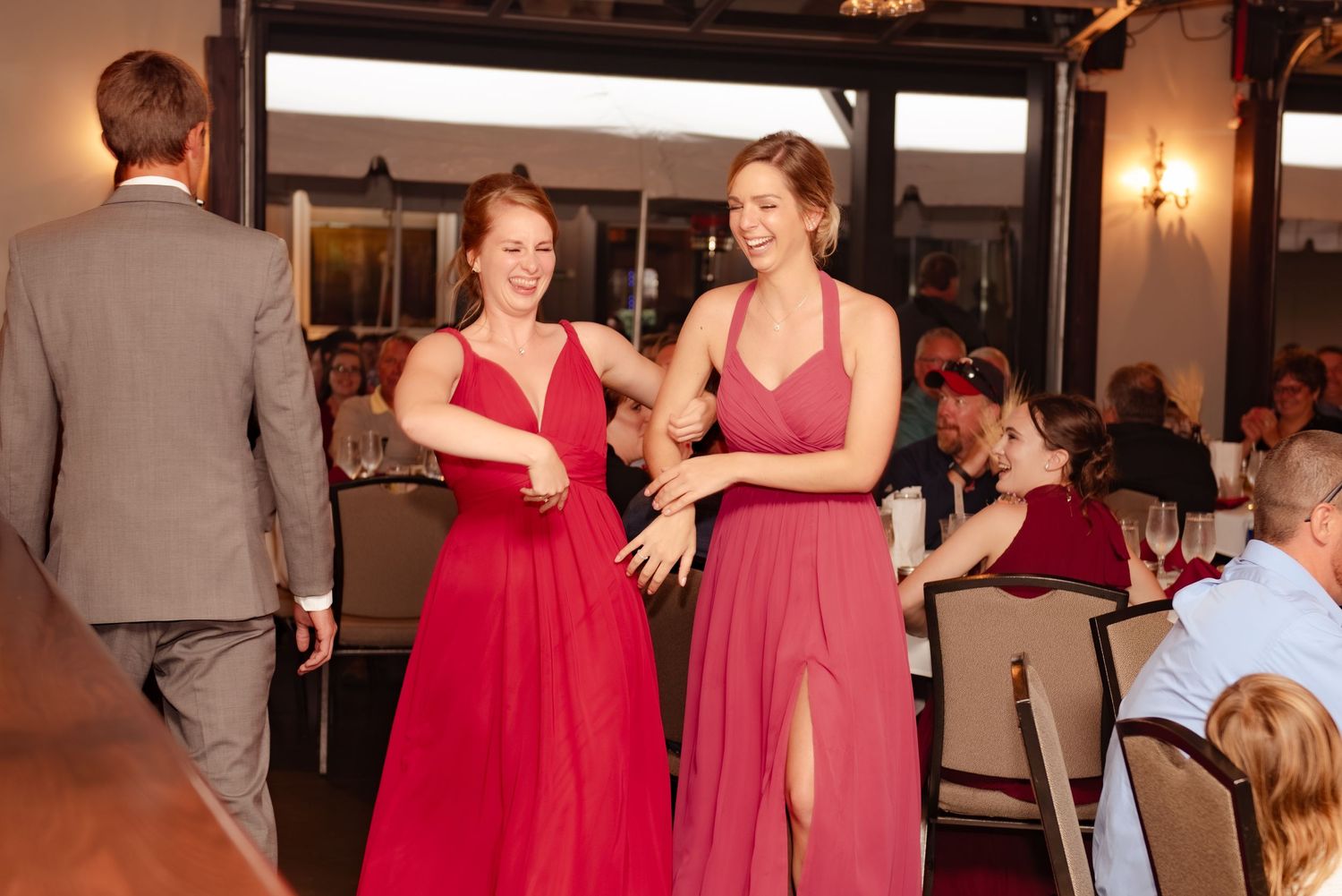 Two attendees in red dresses sharing a joyful moment on the dance floor.