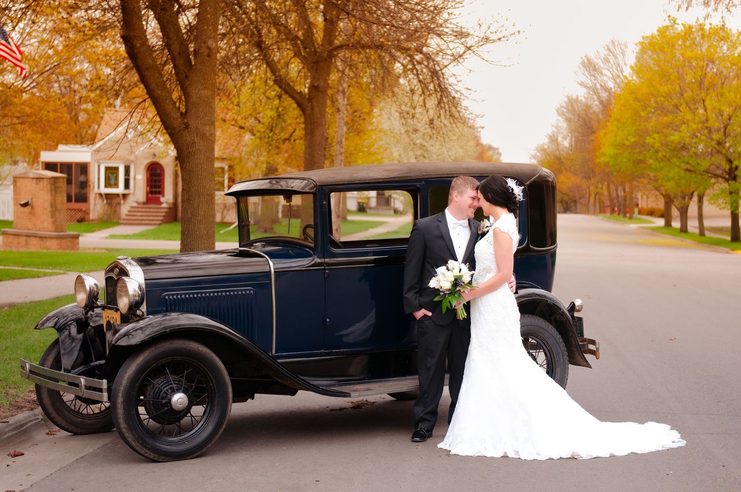 A vintage Model A Ford serves as backdrop for an elegant autumn wedding photo.