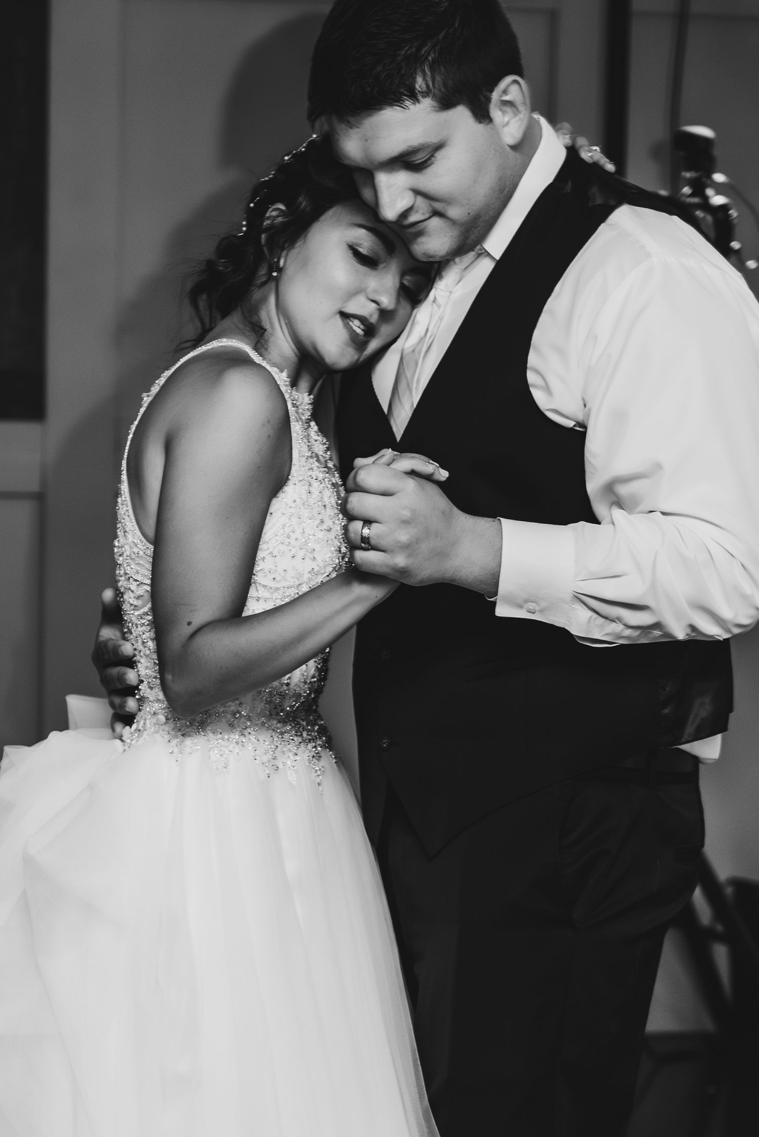 A black and white photo shows a tender slow dance moment at a wedding reception.