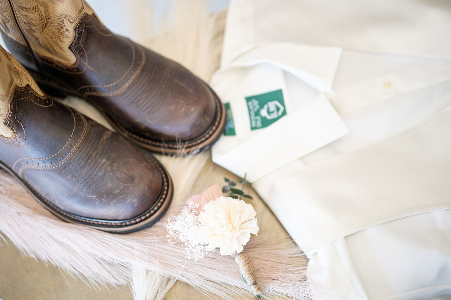 Brown leather boots and delicate lace accessories arranged on white surface.