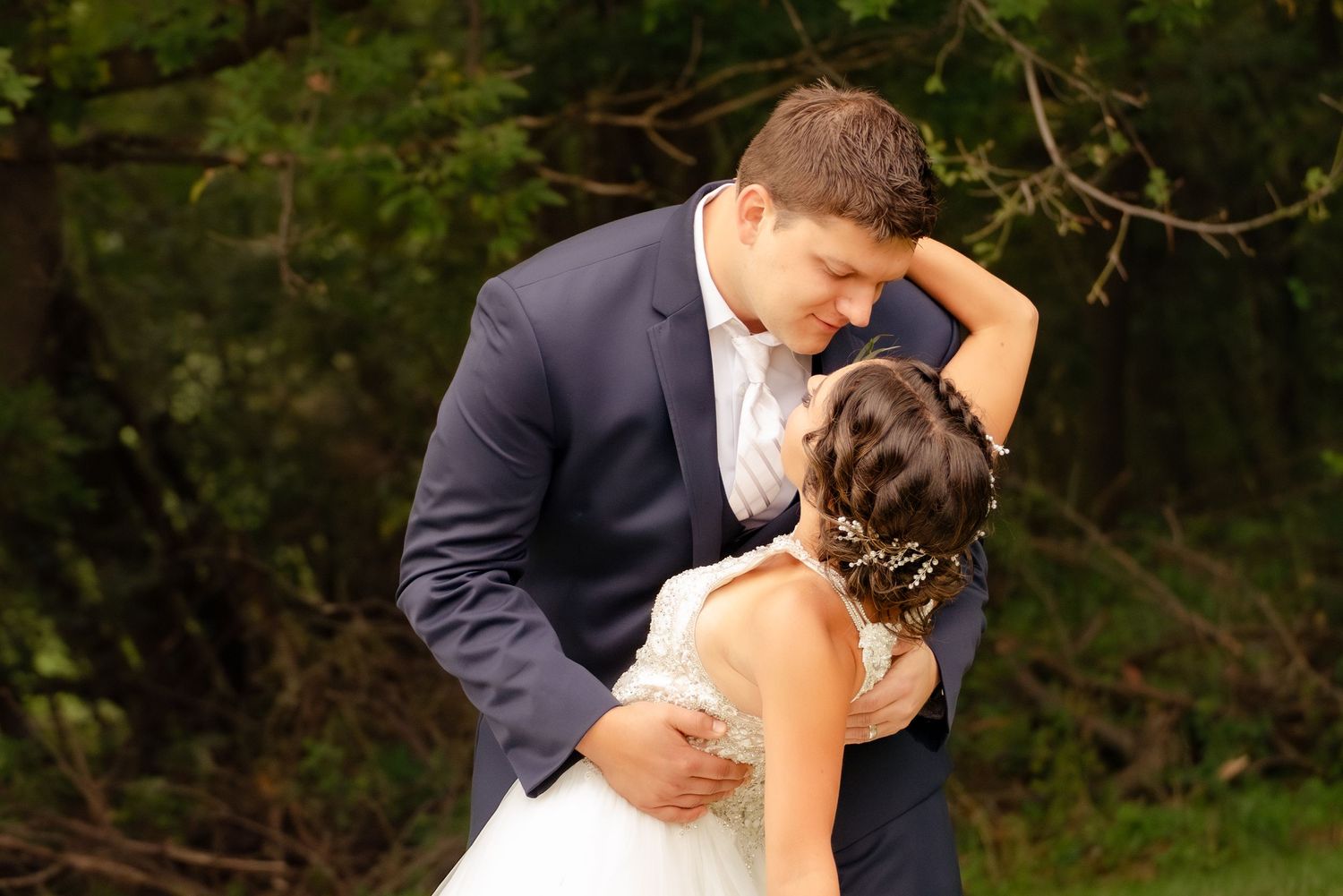 A romantic outdoor wedding portrait showing the couple in an intimate embrace.