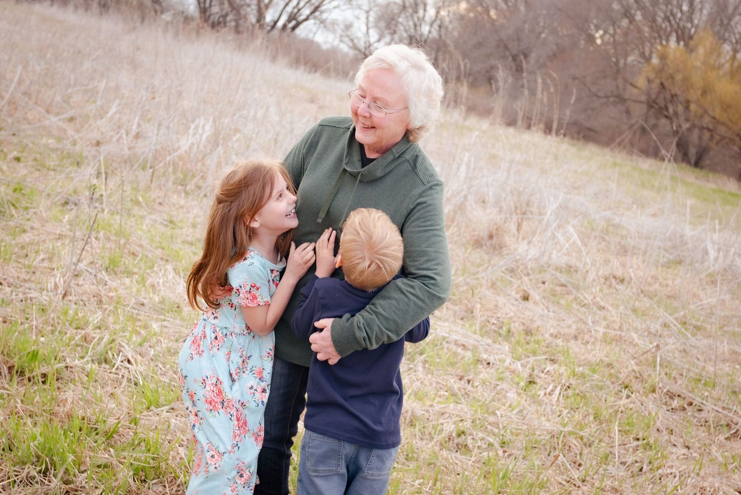 Three generations sharing laughter together in a grassy field.