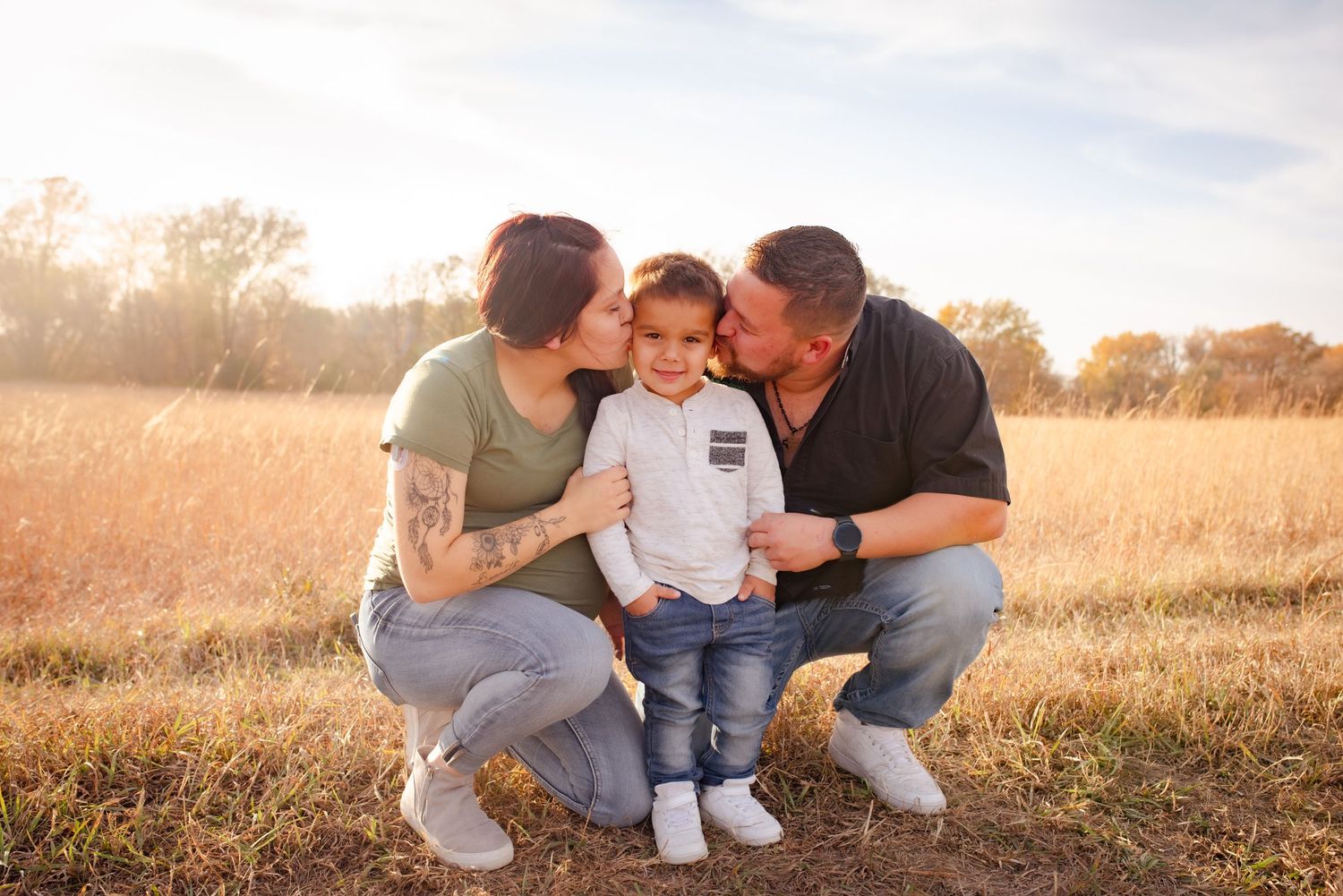 Family sharing an intimate moment together in a golden field at sunset.