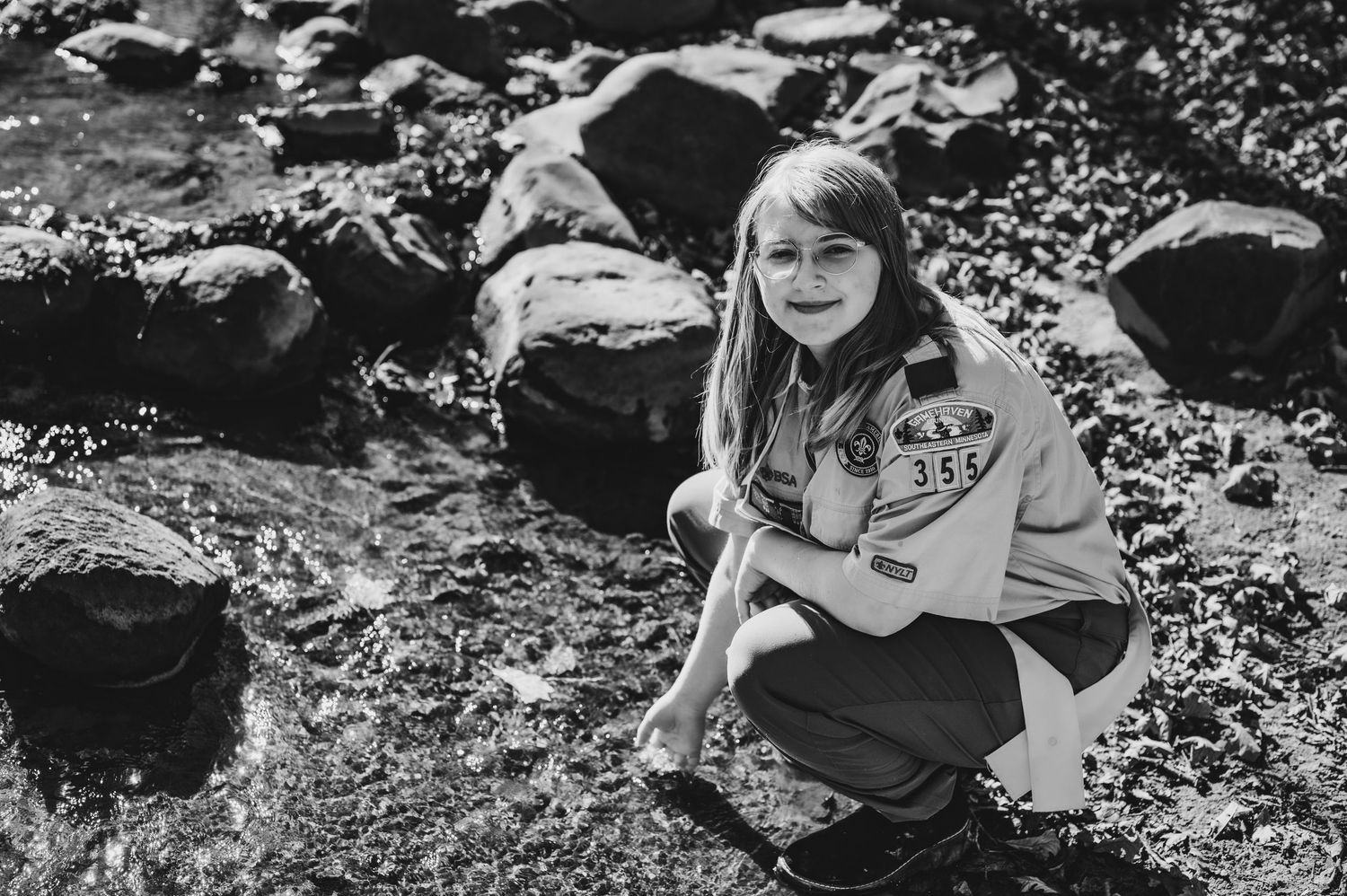 Black and white portrait of person resting on rocky shore with artistic composition.