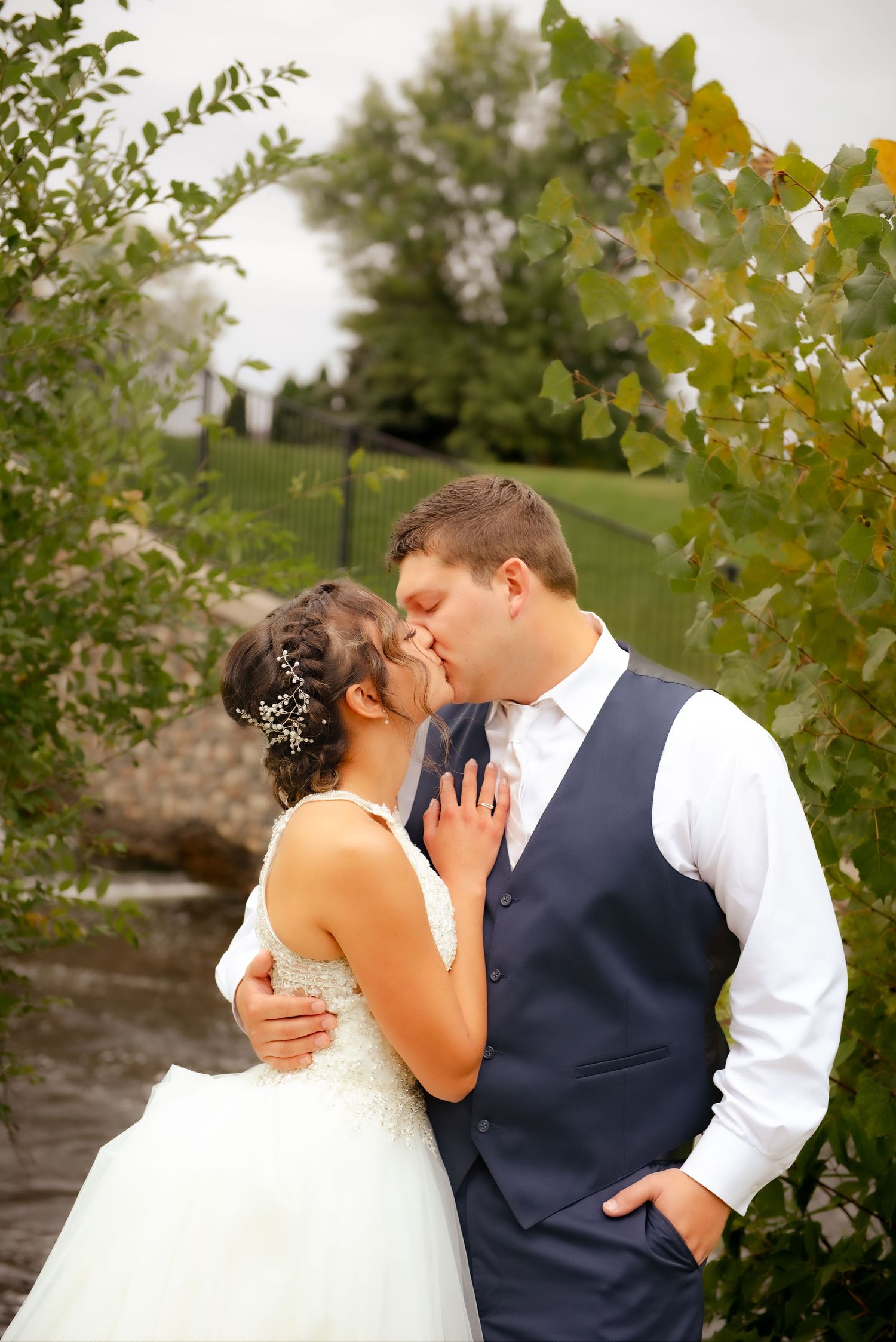 A romantic wedding portrait in a garden with fall foliage and stone wall backdrop.