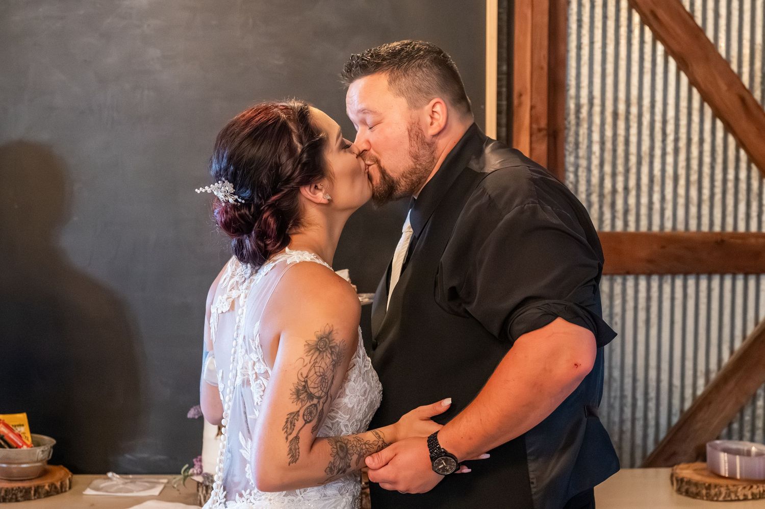 A couple shares their first kiss as newlyweds in a rustic barn venue.