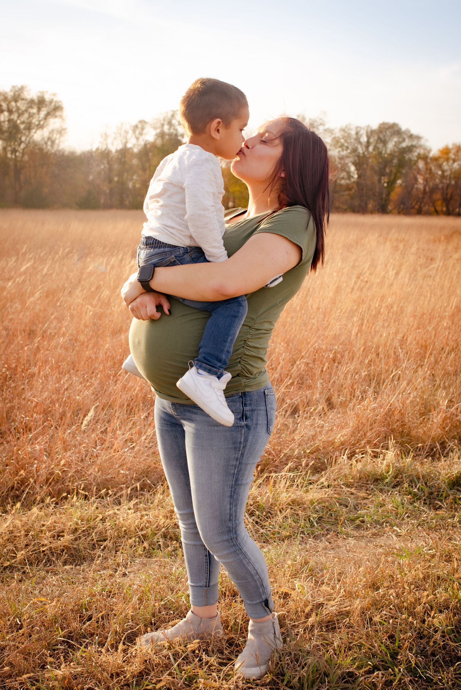 Tender moment between parent and child in a sunlit autumn field.