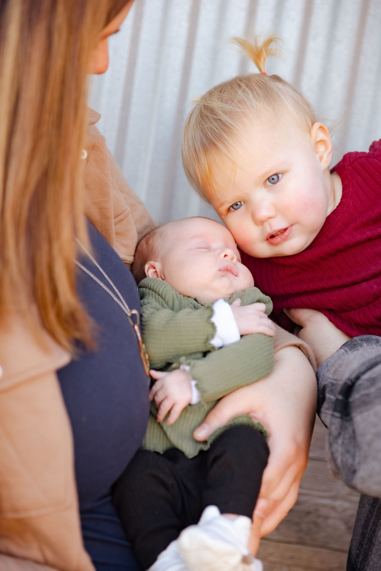 Portrait of siblings with one holding a newborn baby.