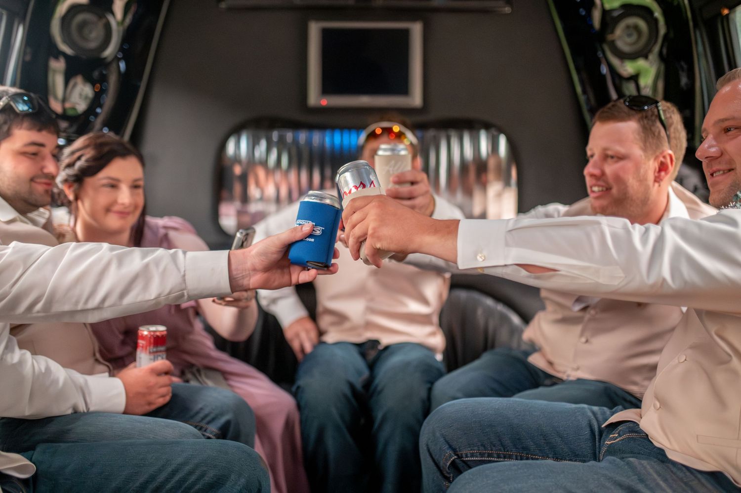 Friends celebrating with drinks in a party bus or limousine interior.