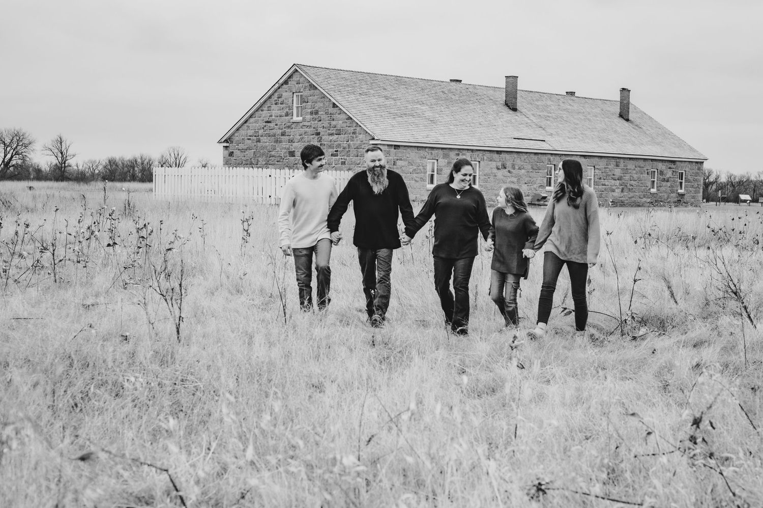 A group walking through a snowy field with an old barn in the background.