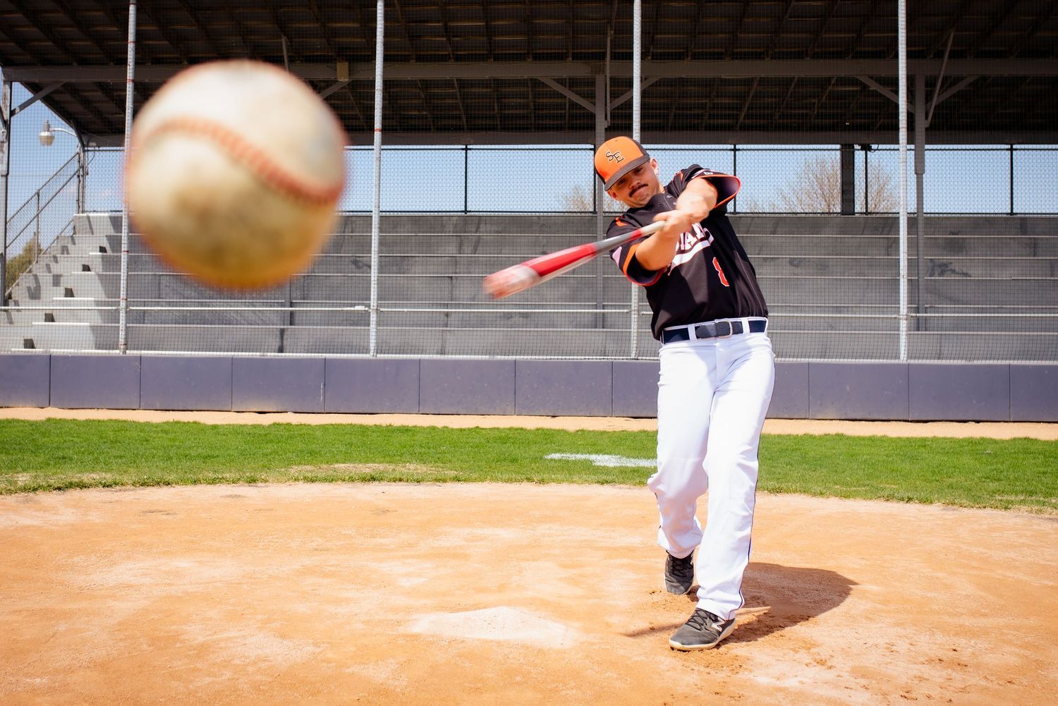 Baseball player swinging bat at ball during game on baseball diamond.