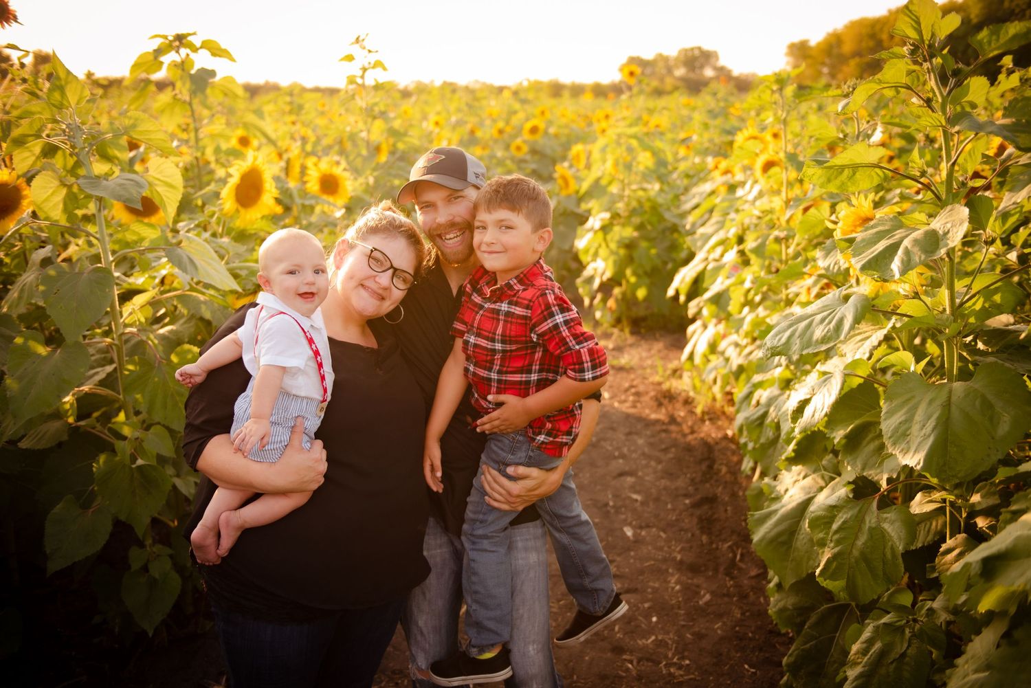 A warm sunset photo in a sunflower field with family silhouettes against the golden evening light.