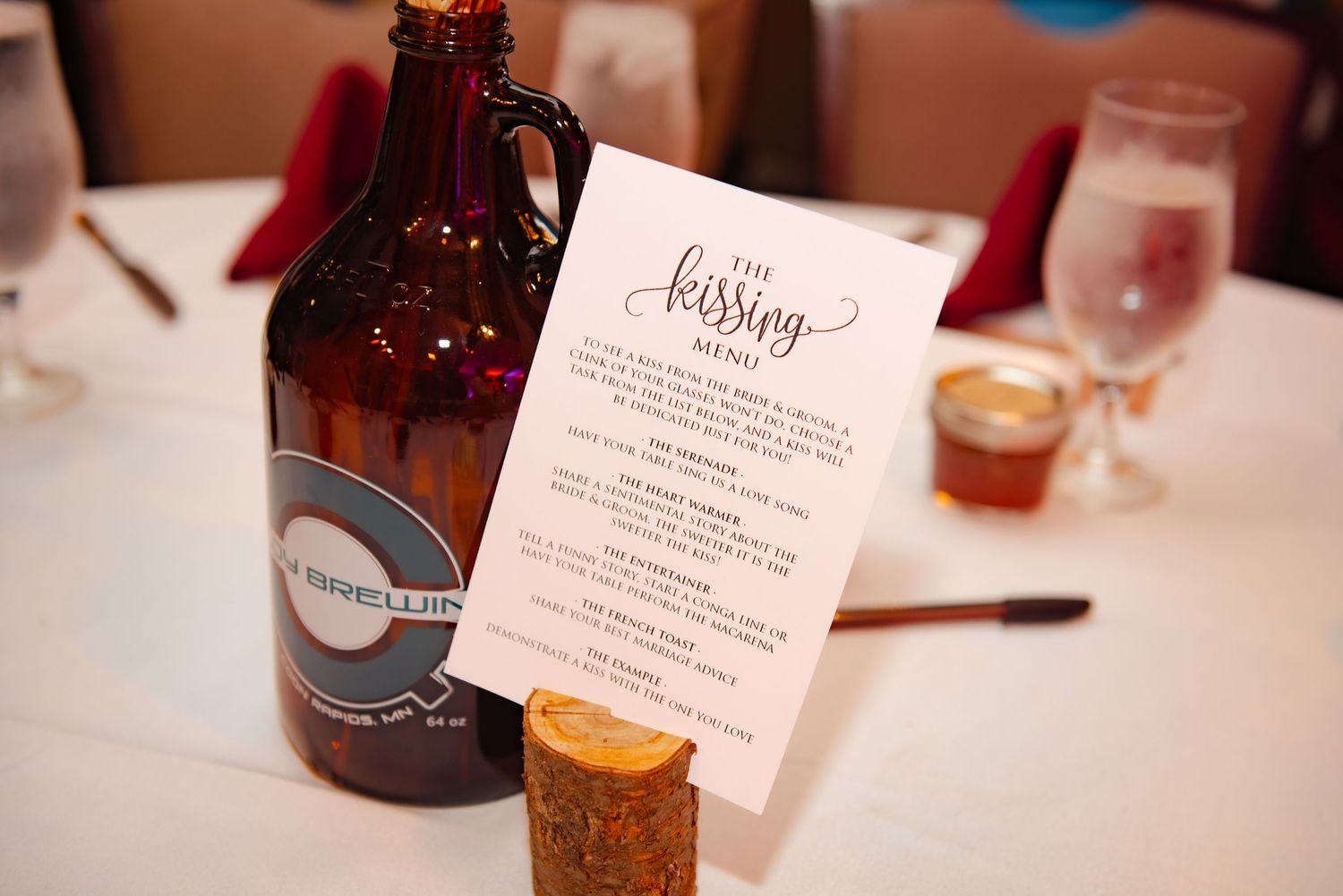 Wedding beverage display with a craft beer bottle and printed menu card on white tablecloth.