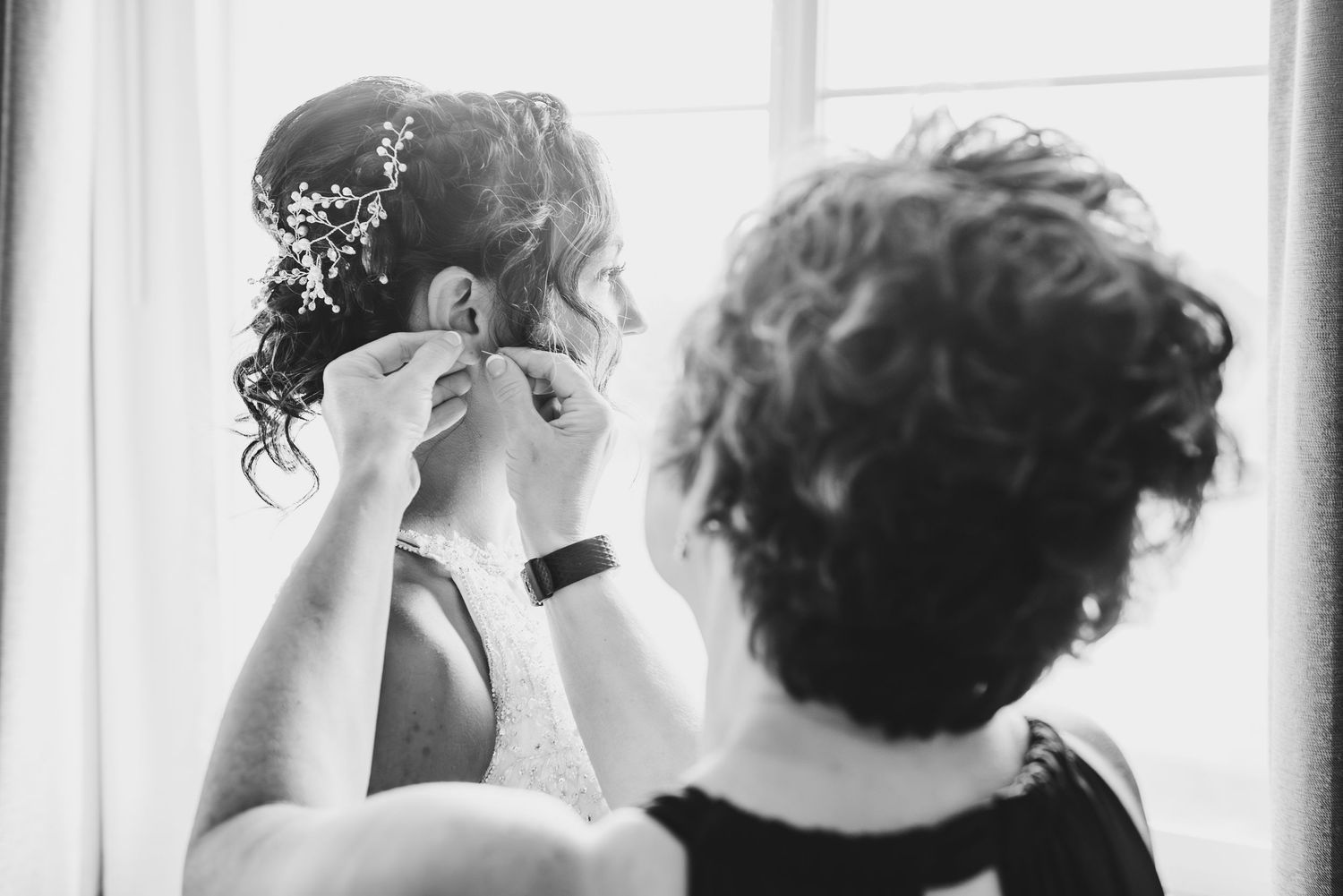 Intimate black and white moment of wedding preparation by window light.