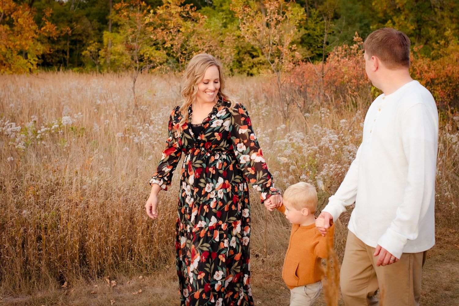 A family enjoys a golden autumn afternoon together in a field of tall grass.