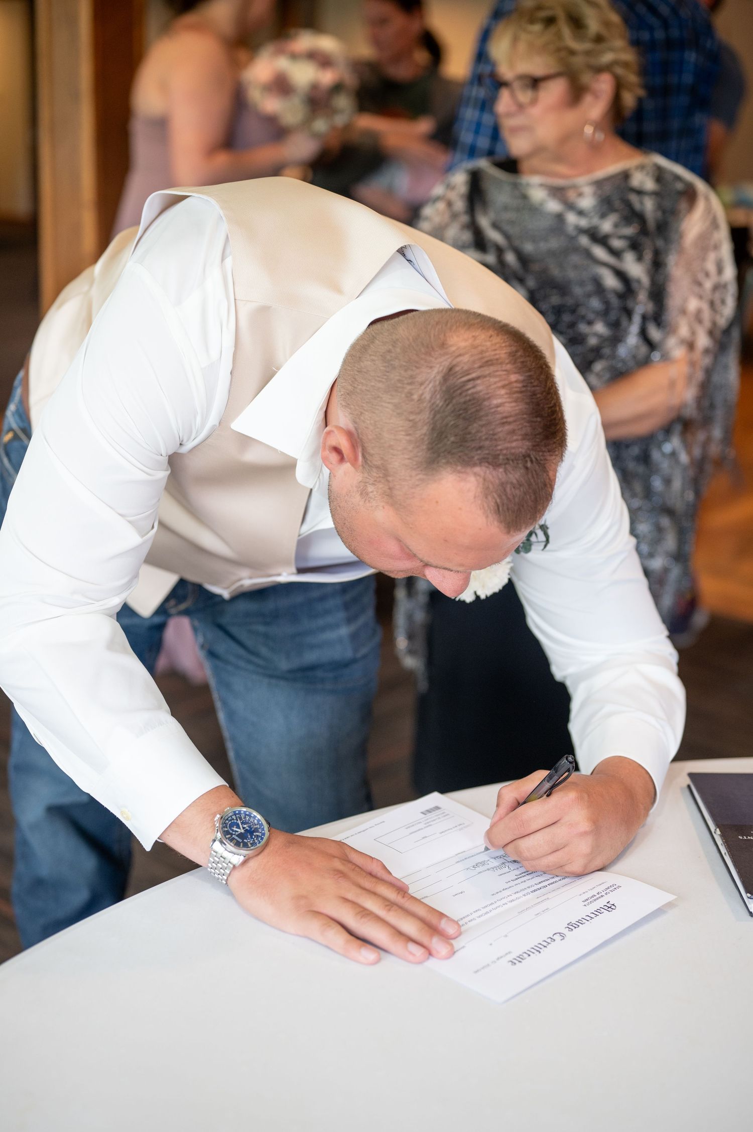 Person in white shirt signing official documents at a table.
