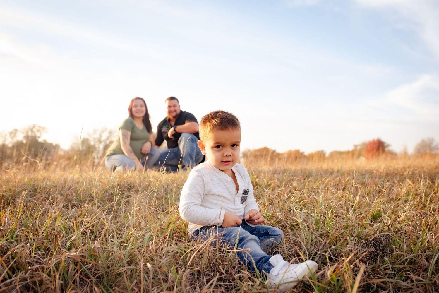 Outdoor family portrait session in a rustic field with tall grass.