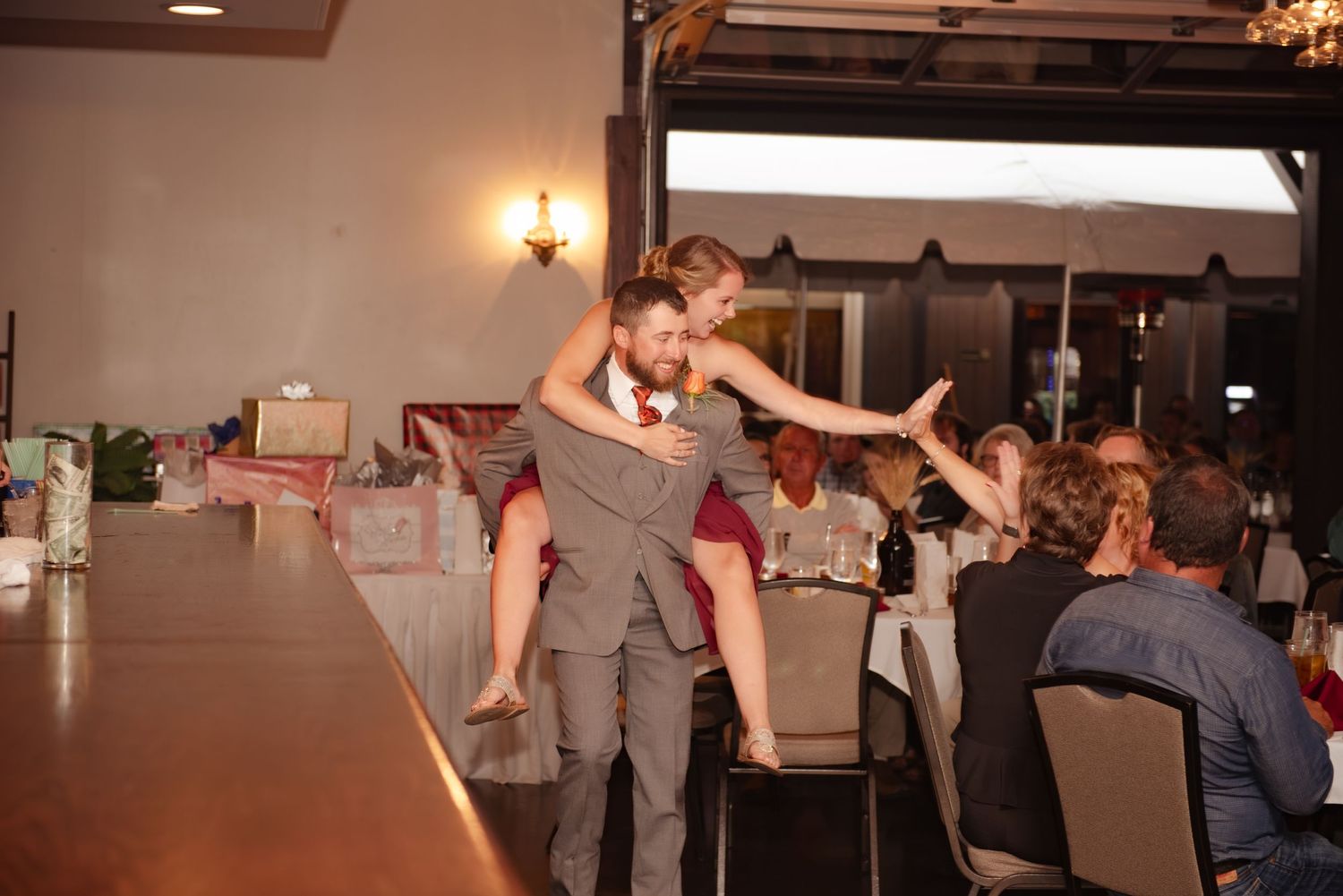Playful wedding reception moment with guests looking on in the background.