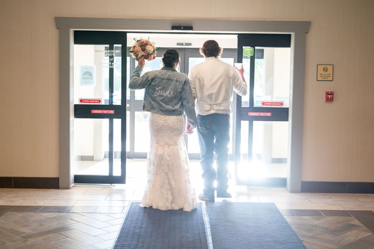 Couple walking hand in hand towards glass exit doors in natural lighting.
