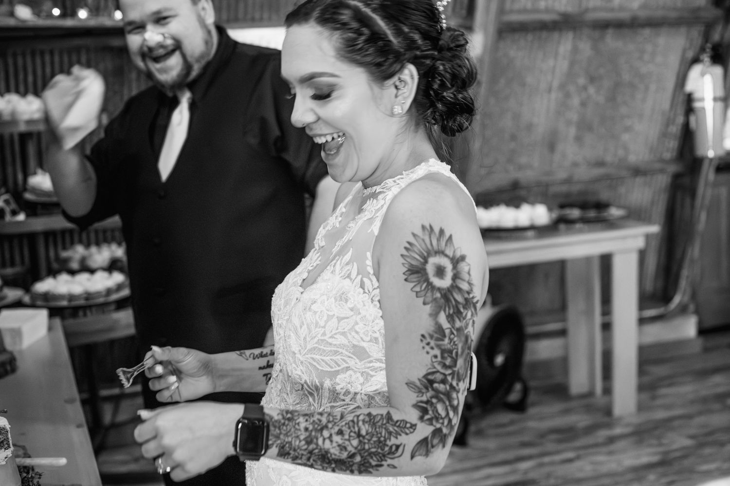 Black and white candid photo of bride laughing during wedding reception.