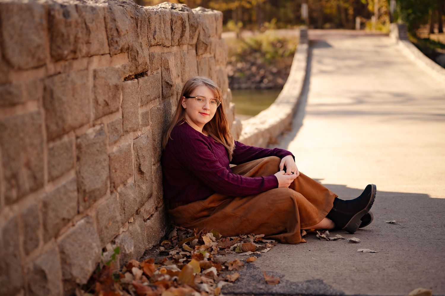 A series of autumn portraits showing someone sitting against a stone wall with fallen leaves scattered around.
