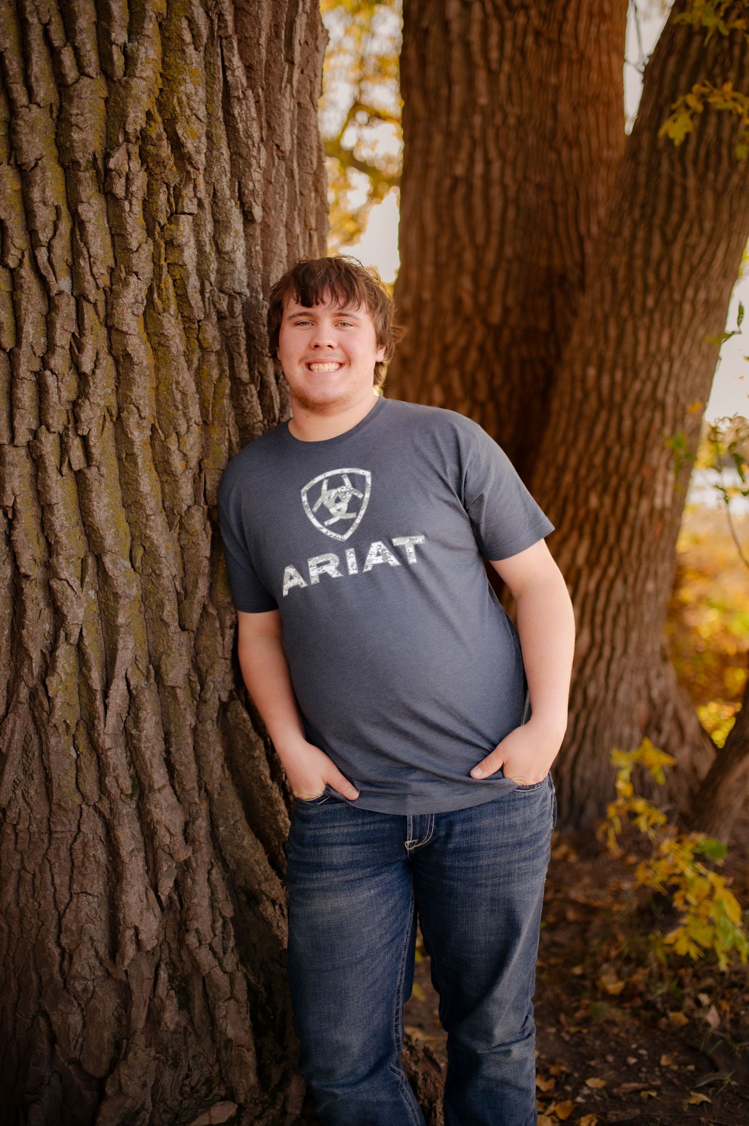 A series of casual outdoor portrait shots against large tree trunks in autumn with warm natural lighting.
