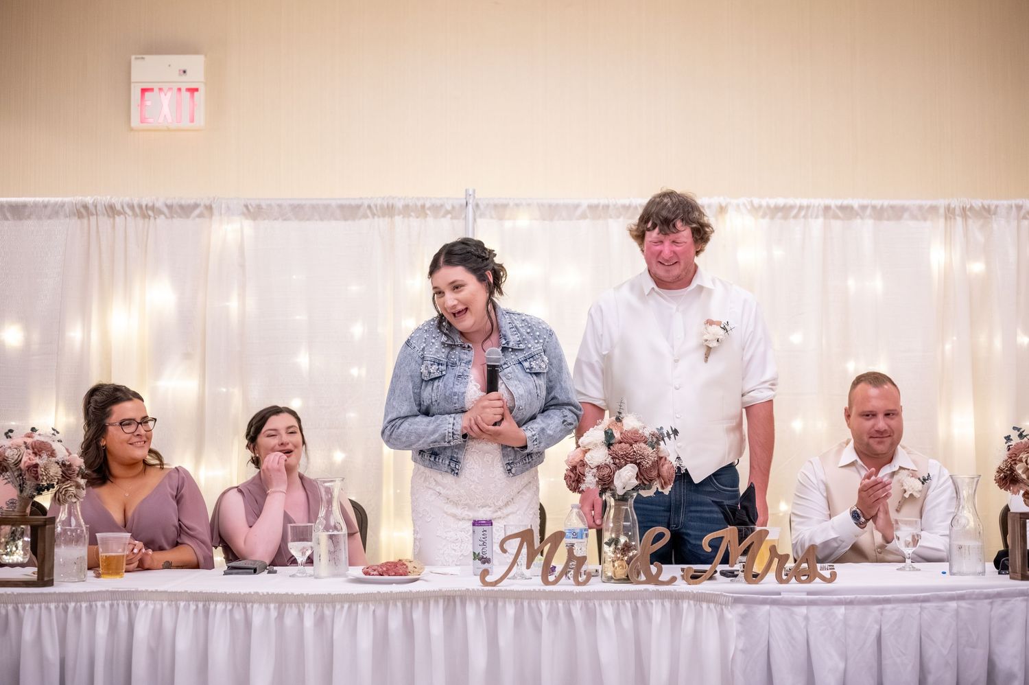Wedding party sharing laughs and applauding during reception speeches.