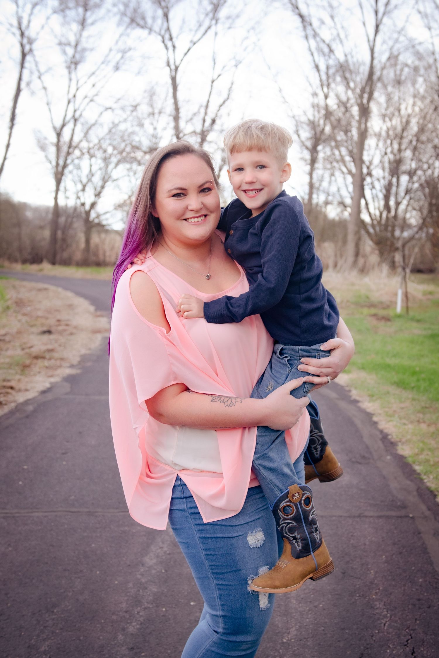 A casual outdoor portrait on a paved trail featuring vibrant pink hair and coordinated outfits.