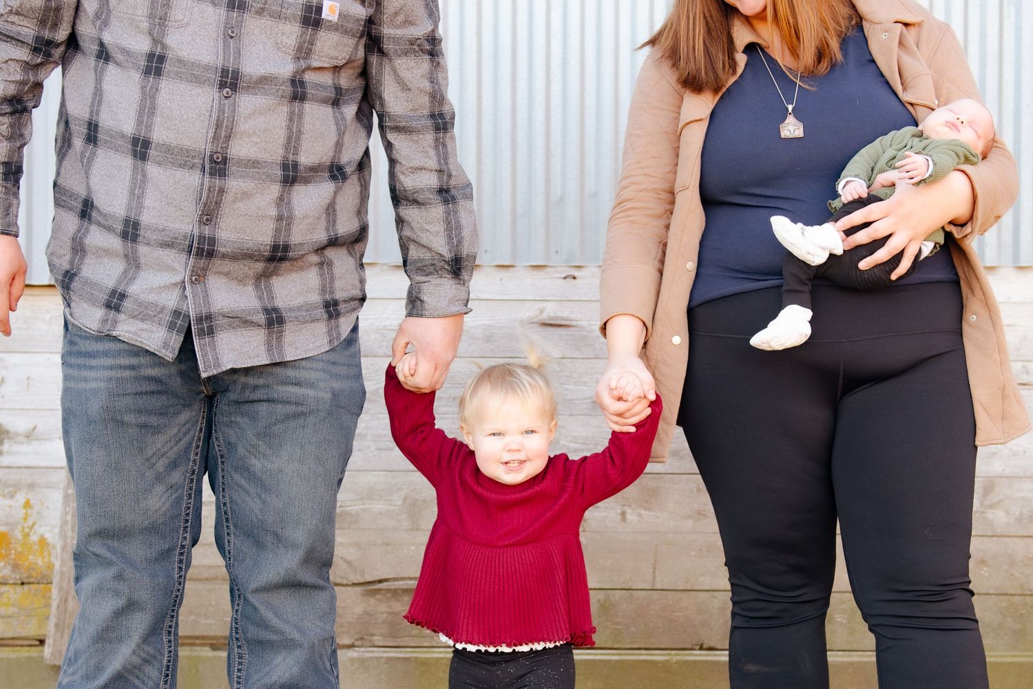 Family portrait with toddler raising arms between parents.