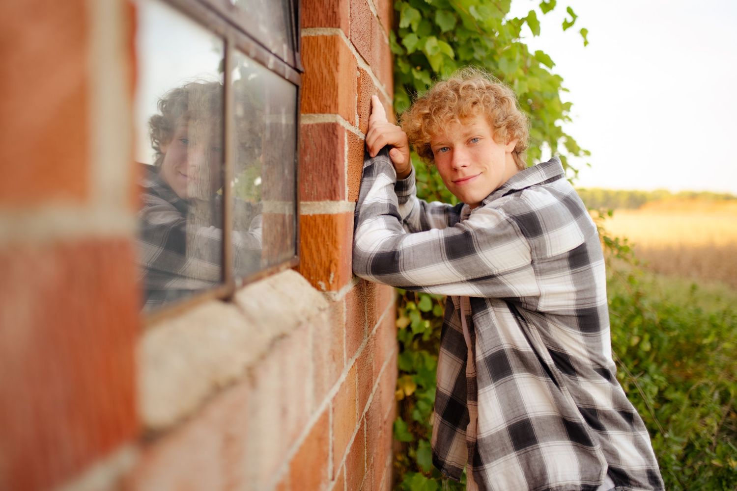 Creative pose looking through window against brick wall wearing plaid flannel shirt.