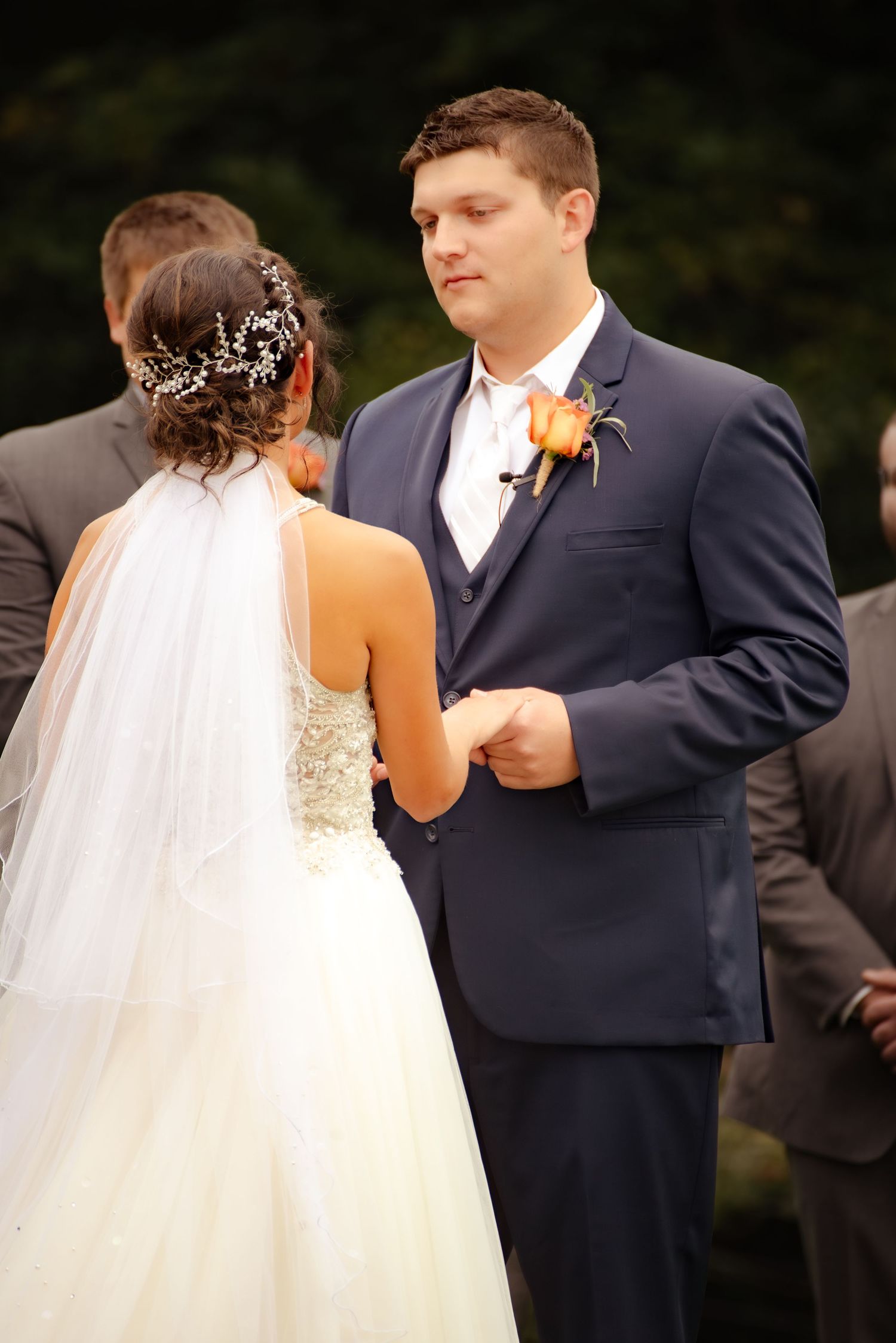 Wedding ceremony moment captured as couple exchanges vows under an outdoor wooden arch.
