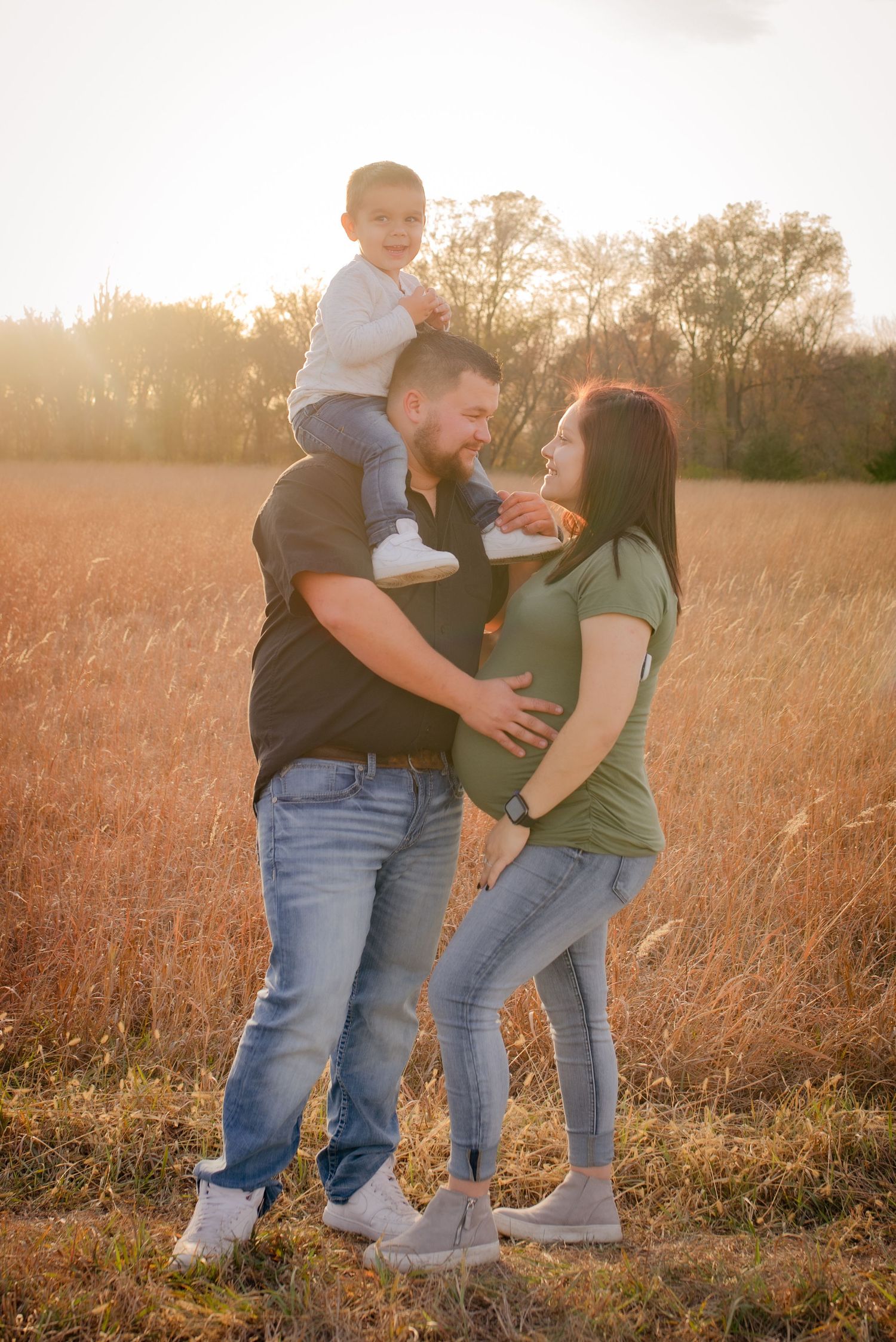 A loving family shares a tender moment in a golden wheat field at sunset.