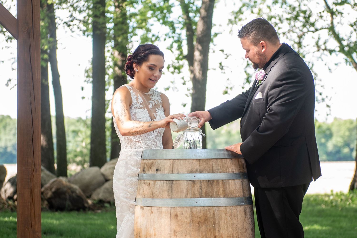 A couple performing a love letter ceremony using a rustic wine barrel at an outdoor wedding.